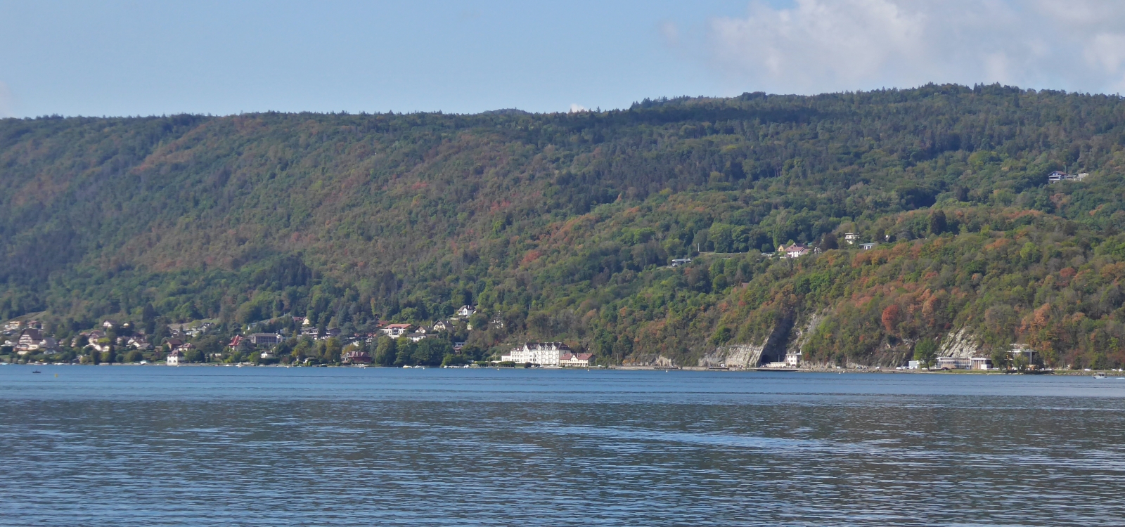 Blick über den See von Annecy auf den herbstfarblichen Wald an den Berghängen. 09.2022