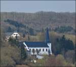 Diverses/260112/-blick-vom-aussichtspunkt-geeselee-in . Blick vom Aussichtspunkt 'Geeselee' in Lellingen nach Pintsch. Die Kirche von Pintsch war im Mittelalter eine der wichtigsten Kirchen des slings, eine der sogenannten Mutterkirchen. Der mchtige Glockenturm stammt aus dem 11. Jahrhundert und ist neben der Sakristei, der lteste Teil des Gebudes. Whrend der Ardennenoffensive 1944/45 wurde das Gotteshaus stark beschdigt, doch schon 1949 war es wieder aufgebaut. 07.04.2013 (Jeanny)