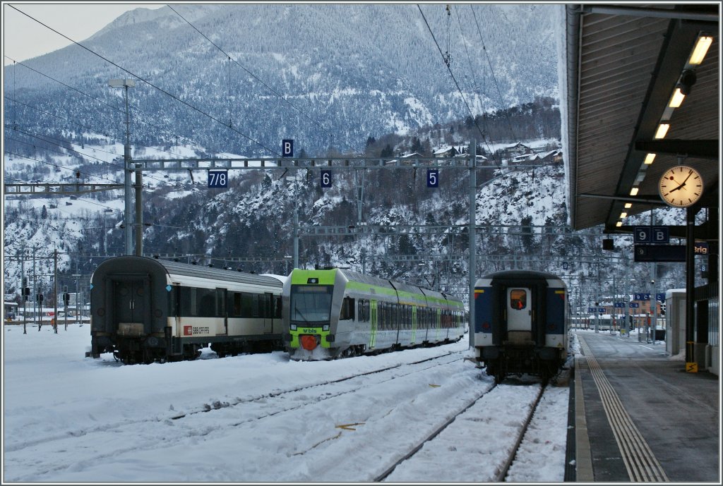 Ein  Ltschberger  flankiert vom einem ex SNCF Gepckwagen und einem EW I/II in Brig. 
Zudem erlaubt das Bild (via Exif-Datei) eine genau Zeitbestimmung...
Brig, den 12.12.12
