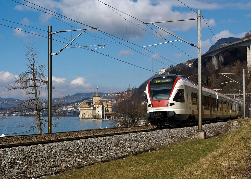 Ein Stadler FLIRT  RABe 523 030 der SBB (RER Vaudois) als S3 (Allaman–Lausanne–Vevey –Montreux–Villeneuve), fhrt am 26.02.2012 bei  Clos du Moulin am Genfersee Richtung Villeneuve, hinten Chteau de Chillon, dahinter Montreux.