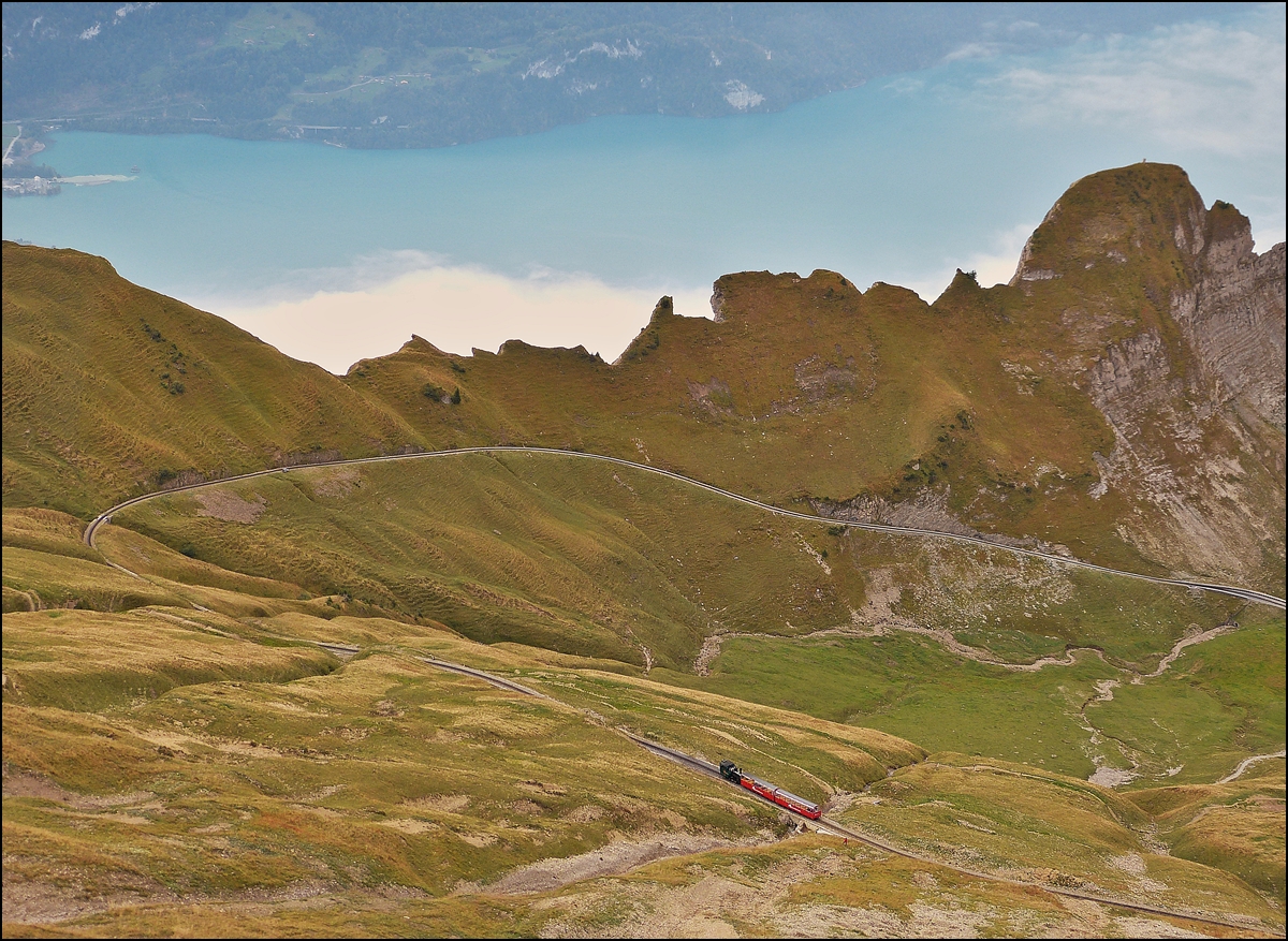 . Kleiner als T-Gauge - Von der Terrasse des Berghauses konnte ich am 29.09.2013 den BRB Zug beobachten, welcher den letzten Streckenabschitt zwischen Oberstafel und Rothorn Kulm in Angriff genommen hatte. Der rote Punkt rechts neben dem Zug ist Heinz auf seiner morgendlichen Wanderung entlang der BRB Strecke. (Jeanny)