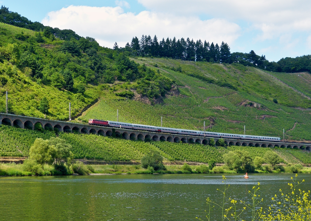 . Wolkenlotto in Pnderich - Die 181 219-7 zieht am 21.06.2014 den IC 132  Norderney  Norddeich Mole - Luxemburg ber das Hangviadukt gegenber von Pnderich. (Hans)

Der Pndericher Hangviadukt ist ein Hangviadukt auf der Moselstrecke gegenber von Pnderich an der Mosel. Das 786 m lange Bauwerk ist der lngste Hangviadukt in Deutschland. Unmittelbar am nrdlichen Ende des Viaduktes beginnt der Prinzenkopftunnel.

Der Hangviadukt ist etwa 10 Meter hoch und weist 92 Bgen auf. Jeder der Bgen hat eine Spannweite von 7,20 m, die Pfeiler sind 1,30 m stark. Die Brcke besteht aus Bruchsteinen aus einem nahegelegenen Steinbruch und Ziegelsteinen, die von Ziegeleien aus Merl und St. Wendel geliefert wurden. Insgesamt wurden 19.000 m3 Mauerwerk verbaut.

Die Vermessungsarbeiten im Bereich des Viaduktes begannen im Februar 1872. In den Jahren 1877 und 1878 wurde zunchst der Viadukt fr das moselseitige Gleis gebaut und am 15. Mai 1879 mit der Erffnung der Untermoselbahn in Betrieb genommen. Die von vornherein geplante bergseitige Erweiterung wurde in den Jahren 1879 und 1880 gebaut. Am 7. Oktober 1880 fand anlsslich der Fertigstellung der Brcke ein Schlusssteinfest statt.

Gegen Ende des Zweiten Weltkrieges sprengten deutsche Truppen auf dem Rckzug vier Bgen des Viaduktes. Die Reparaturarbeiten wurden nach Kriegsende mit Hilfe dienstverpflichteter Arbeitskrfte begonnen. Das moselseitige Gleis war am 1. September 1946 wieder befahrbar und bei der Wiederinbetriebnahme der Moselstrecke am 24. April 1947 war der Pndericher Viadukt wieder vollstndig hergestellt.

Bei Bauarbeiten im Jahr 1952 wurde eine Urkunde gefunden, die beim Schlusssteinfest eingemauert worden war. Diese fhrt alle Dienststellen und Firmen auf, die sich beim Bau beteiligt hatten und das Dokument vergleicht die damaligen Baukosten mit denen fr Lebensmittel wie Brot, Fleisch und Moselwein. Eine Moselweinflasche kostete damals je nach Qualitt zwischen 1 und 5 Mark.

Anfang der 1970er Jahre wurden bei der Elektrifizierung der Moselstrecke die Gleise auf dem Viadukt tiefer gelegt, wozu kleinere Sprengarbeiten ntig waren. Dies war erforderlich, weil das Niveau der Brckengleise an das der Gleise im anschlieenden Prinzenkopftunnel angepasst werden musste, welche ebenfalls abgesenkt wurden, damit gengend Raum fr die Fahrleitung im Tunnel geschaffen werden konnte.

Im Rahmen der Feierlichkeiten zum 175. Geburtstag der deutschen Eisenbahn im Jahr 2010 wurde der Hangviadukt vom 2. bis 5. April beleuchtet und von Sonderzgen auf der Moselstrecke und der Nebenbahn nach Traben-Trarbach befahren.
 



