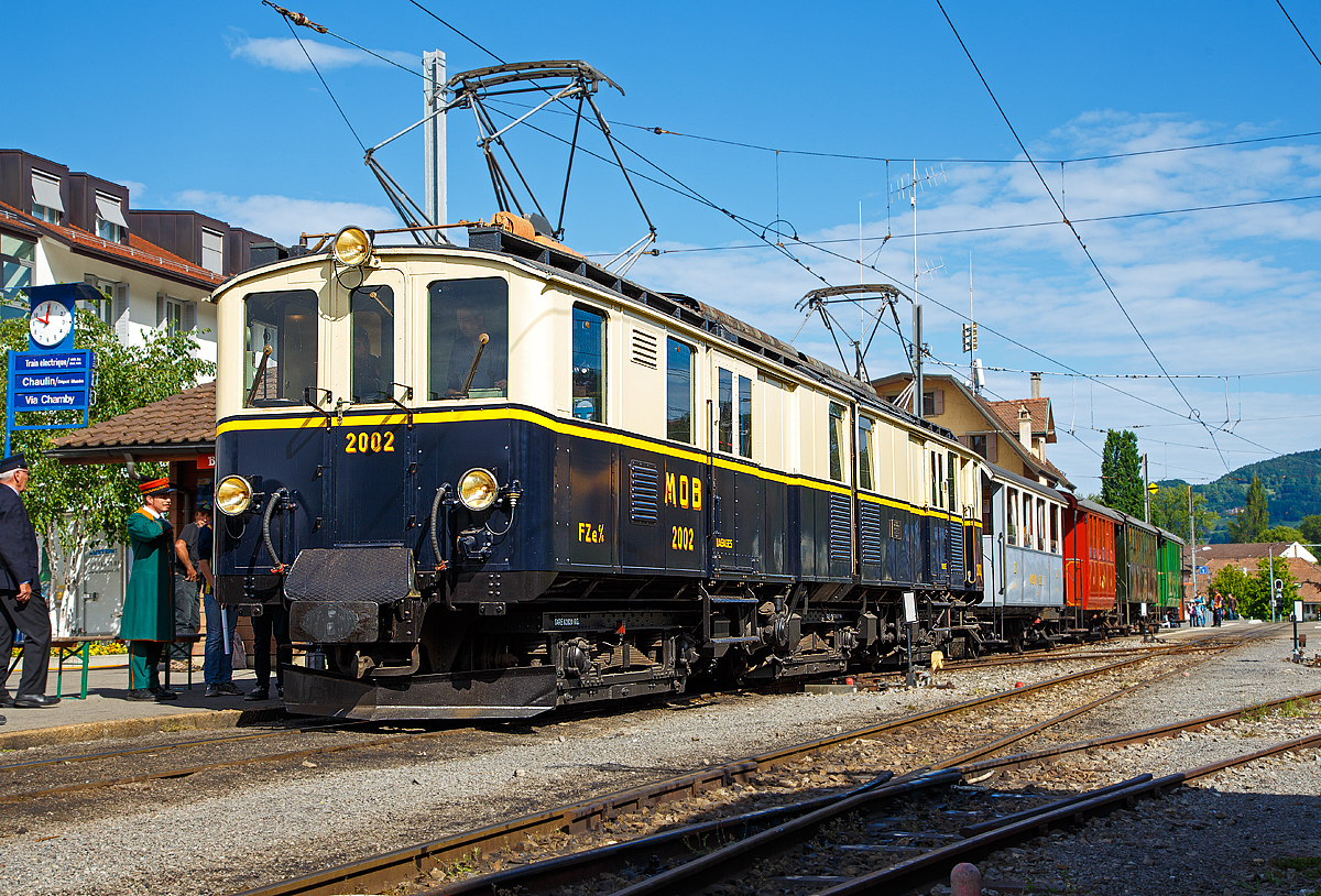 
50 Jahre BC - MEGA STEAM FESTIVAL der Museumsbahn Blonay–Chamby:
Bevor wir nach Vevey herunter „surften“...
Konnten wir noch im tollen Morgenlicht den wunderschöne Gelenktriebwagen ex MOB DZe 6/6 2002, bzw. FZe 6/6 2002 bestaunen und fotografieren. Hier steht er am 21.05.2018 im Bahnhof Blonay mit einem Zug zur Abfahrt zum Museum bereit.

Der Triebwagen Gepäck- und Postabteil wurde 1932 von SIG unter der Fabriknummer 3703 gebaut, der Elektrische Teil ist von BBC. Der Gepäcktriebwagen wurde 1996 in der Remise Gstaad Abgestellt und gedamelte vor sich hin, bis er im Juli 2008 zur Museumsbahn Blonay–Chamby ging.

Die MOB (Montreux–Berner Oberland-Bahn) beschaffte für die Bespannung des “Golden Mountain Pullman Express” die beiden zweiteiligen Gelenktriebwagen FZe 6/6 2001 und 2002 (MOB-intern immer „Lokomotiven“ bzw. „Gepäcklokomotiven“ genannt). Nachdem der Expresszug schnell wieder eingestellt wurde (vor der Lieferung), fanden die beiden Gelenktriebwagen ein neues Betätigungsfeld im schweren Schnellzug- und Güterzugverkehr bzw. bespannten Sonderzüge mit den bei der MOB verbliebenen Salonwagen.

Riesig sind sie, mit immerhin 17 m Länge, sind diese Gelenktriebwagen eine eindrucksvolle Erscheinung. Bis zur Einführung der Baureihe GDe 4/4 6000, also rund fünfzig Jahre lang, waren sie außerdem mit ihren rund 1.000 PS die leistungsstärksten Gleichstrom-Lokomotiven der Schweiz. 

Die ursprüngliche Bezeichnung war „FZe 6/6“ (Triebwagen mit Gepäck- (F) und Postabteil (Z)) wurde später in „DZe 6/6“ geändert. Eine solche Umzeichnung fand europaweit irgendwann nach dem 1. Januar 1962 statt, sie entsprach dem RIC-Reglement (Regolamento Internazionale Carrozze, ein Übereinkommen über die gegenseitige Benutzung der Personen- und Gepäckwagen im internationalen Verkehr). 

Die beiden Fahrzeuge 2001 und 2002, trugen nie irgendwelche Wappen oder Namen, sie behielten allerdings bis heute die Pullman-Lackierung in dunkelblau/crème mit gelbem Seitenstreifen

TECHNISCHE DATEN:
Fahrzeugbezeichnung: DZe 6/6 bzw. (FZe 6/6)
Anzahl Fahrzeuge: 2  (2001 und 2002)
Inbetriebsetzung: 1932
Spurweite: 1.000 mm
Achsanordnung: Bo'Bo'Bo' 
Dienstgewicht: 62,8 t
Länge über Kupplung: 17.000 mm
Kastenlänge: 2 x 7.850 mm
Fahrzeughöhe: 3.550 mm
Fahrzeugbreite: 2.700 mm
Drehgestellabstand: 2 x 5.500 mm
Achsabstand im Drehgestell: 2.300 mm
Treibraddurchmesser (neu): 945 mm
Höchstgeschwindigkeit: 55 km/h
Maximale Leistung am Rad 	6 x 132 kW = 738 kW	
Getriebeübersetzung: 1:6.94
Ladefläche Gepäck- / Postraum: 10 m² / 8 m²	 (4t)
Stromsystem: 900 V DC
