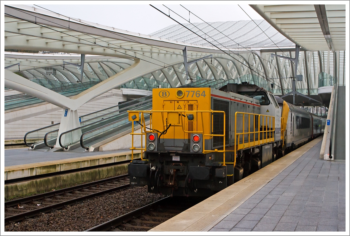 Auf der Bestandsstrecke liegt in der Ausfahrt des Bahnhofs Lttich (Lige Guillemins), Richtung Brssel, eine Steigung von 35 Promille, darum muss bei langen IC-Zgen eine Diesellok Schubhilfe leisten. Hier leistet die SNCB/NMBS HLD 7764   Toledo  am 23.11.2013 Schubhilfe. Die Lok wurde 2002 unter der Fabriknummer 1000981 bei Vossloh in Kiel gebaut, sie trgt die NVR-Nummer NVR-Nummer: 92 88 0077 064-8 B-B. 

Die HLD77 ist eine speziell auf die Belange der Belgischen Staatsbahn (SNCB) zugeschnittene Weiterentwicklung der G 1205. Zwischen 1999 und 2005 wurden insgesamt 170 Lokomotiven an die SNCB geliefert, zudem haben sie einen belgischen Anglo-Belgian Cooperation 6-Zylinder-Dieselmotor vom Typ 6DZC-1000-144A mit 1.150 KW Leistung.