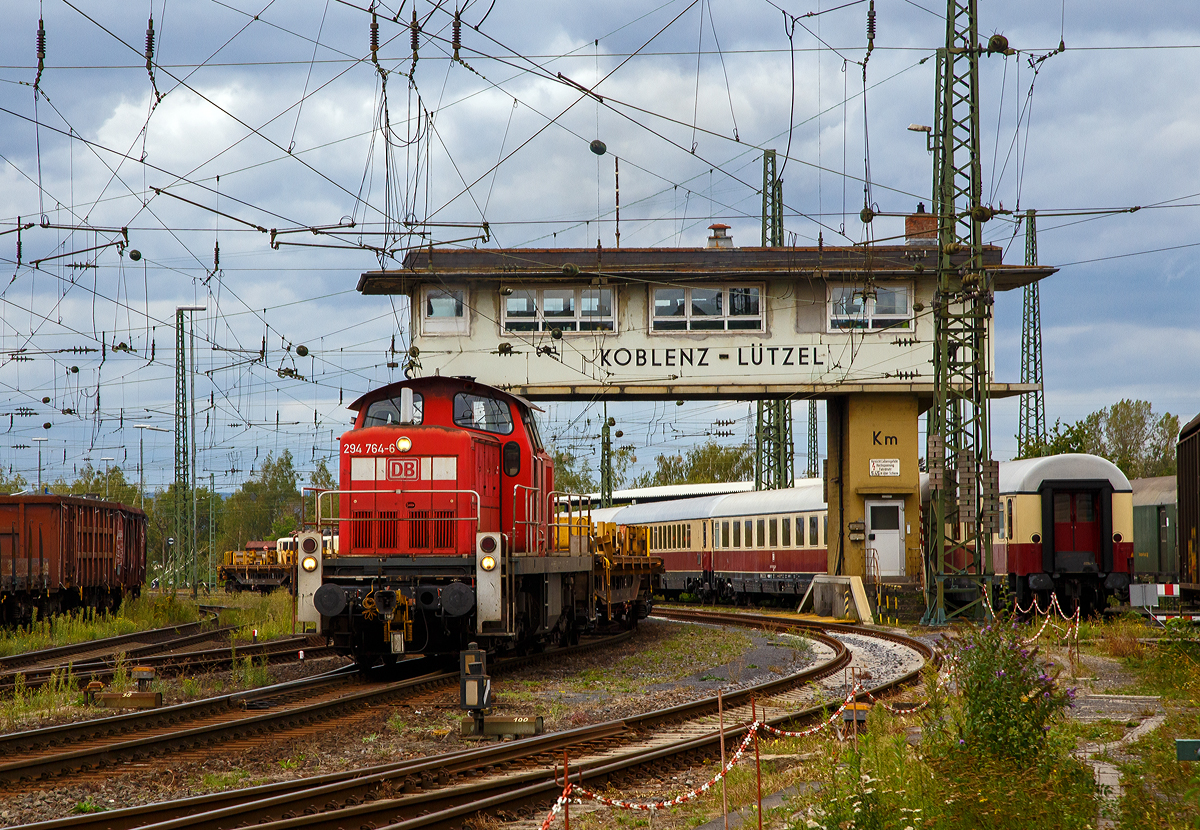 Bei bzw. unter den Reiterstellwerk Koblenz-Lützel Km rangiert am 04.09.2020 die 294 764-6 (98 80 3294 764-6 D-DB), ex DB 290 764-0, ex DB 290 264-1, eine remotorisierte V 90 der DB Cargo AG, mit einem leeren Schienenzug. Das elektromechanische Weichenwärter-Stellwerk, der Bauform Siemens & Halske S&H 1912 (alte Farbscheibenanordnung) ist noch in Betrieb. (Aufnahme aus dem DB Museum heraus).

Die Lok wurde 1972 bei MaK in Kiel unter der Fabriknummer 1000562 gebaut und als 290 262-2 an die DB geliefert. Anders als so viele V 90 fuhr sie recht lange ohne Funkfernsteuerung und wurde erst zur 290 764-0 remotorisiert, bevor sie eine 294er wurde.

 Im Jahr 2002 erfolgte durch die DB Fahrzeuginstandhaltung GmbH, in Cottbus eine Remotorisierung durch einen neuen MTU 90° V-8-Zylinder-Dieselmotor mit Common-Rail-Einspritzsystem, Abgas-Turbolader und Ladeluftkühlung, vom Typ 8V 4000 R41. Der Motor ist auf eine Leistung von 1.000 kW (1.341 PS) bei 1.800 U/min gedrosselt. Auch wurden eine neue Lüfteranlage und ein neuer Luftpresser eingebaut, zudem bekam die Lok ein Umlaufgeländer. Durch die Remotorisierung und den Umbau erfolgte auch die Umzeichnung in 290 764-0. 

Erst 2004 erfolgte dann die Ausrüstung mit Funkfernsteuerung (Typ Krauss-Maffei) und Umzeichnung in die heutige 294 764-6.
