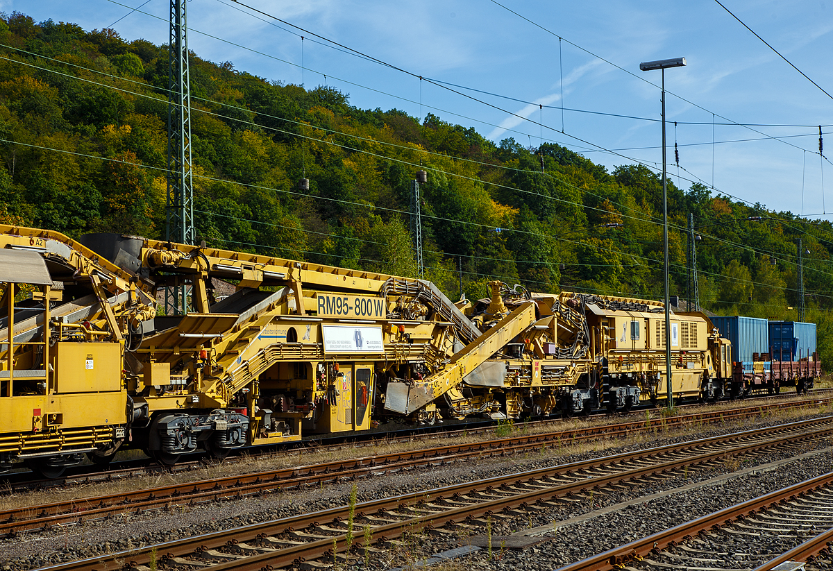 
Bild 2
Die Plasser & Theurer Bettungsreinigungsmaschine RM 95-800 W der MGW Gleis- und Weichenbau-Gesellschaft mbH & Co. KG (Berlin) ist am 20.09.2020 im Bahnhof Dillenburg abgestellt. Hier der Bereich der  Reinigungsmaschine AHM  und ATH. In der linken Einheit (AHM) befindet sich die Aushubkette und die Schotterrückführung (recycelt oder recycelter mit neuen Schotter vermischt).

Die Grundmaschine wurde 2010 von Plasser & Theurer unter den Fabriknummern 5221 bis 5224 gebaut, sie hat die VDM Nr. 99 80 9414 001-4 D-MWGB.
Rechts am Zugende noch der Schutzwagen 3999 010-6 der Gattung Res.