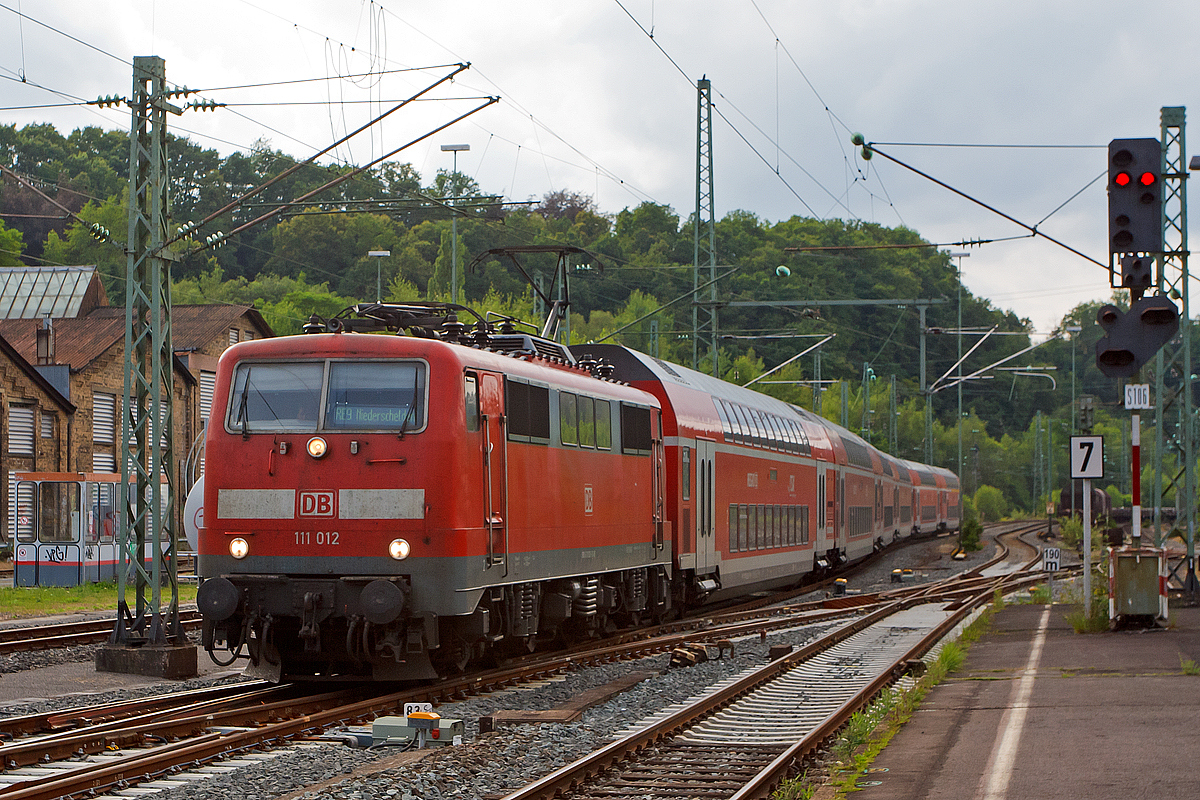 
Bis Mitte August 2014 ist für den RE 9 (rsx - Rhein-Sieg-Express) in Niederschelden Endstation, der Grund dafür ist der Weiterbau der Hüttentalstraße (HTS) als B 62. Diese Hochstraße überquert in Niederschelden die Siegstrecke (KBS 460). 
Hier fährt die 111 012-1 der DB Regio NRW mit sechs Doppelstockwagen als RE 9  rsx - Rhein-Sieg-Express  (Aachen- Köln - Niederschelden) am 13.07.2014 in den Bahnhof Betzdorf/Sieg ein. 

Ungewöhnlich ist das eine 111er mit sechs DoSto´s fährt. 

Die Lok wurde 1975 von Krauss-Maffei in München unter der Fabriknummer 19749 gebaut, der elektrische Teil ist von Siemens. Sie hat seit 2007 die NVR-Nummer 91 80 6111 012-1 D-DB und die EBA-Nummer EBA 01C20A 012.
