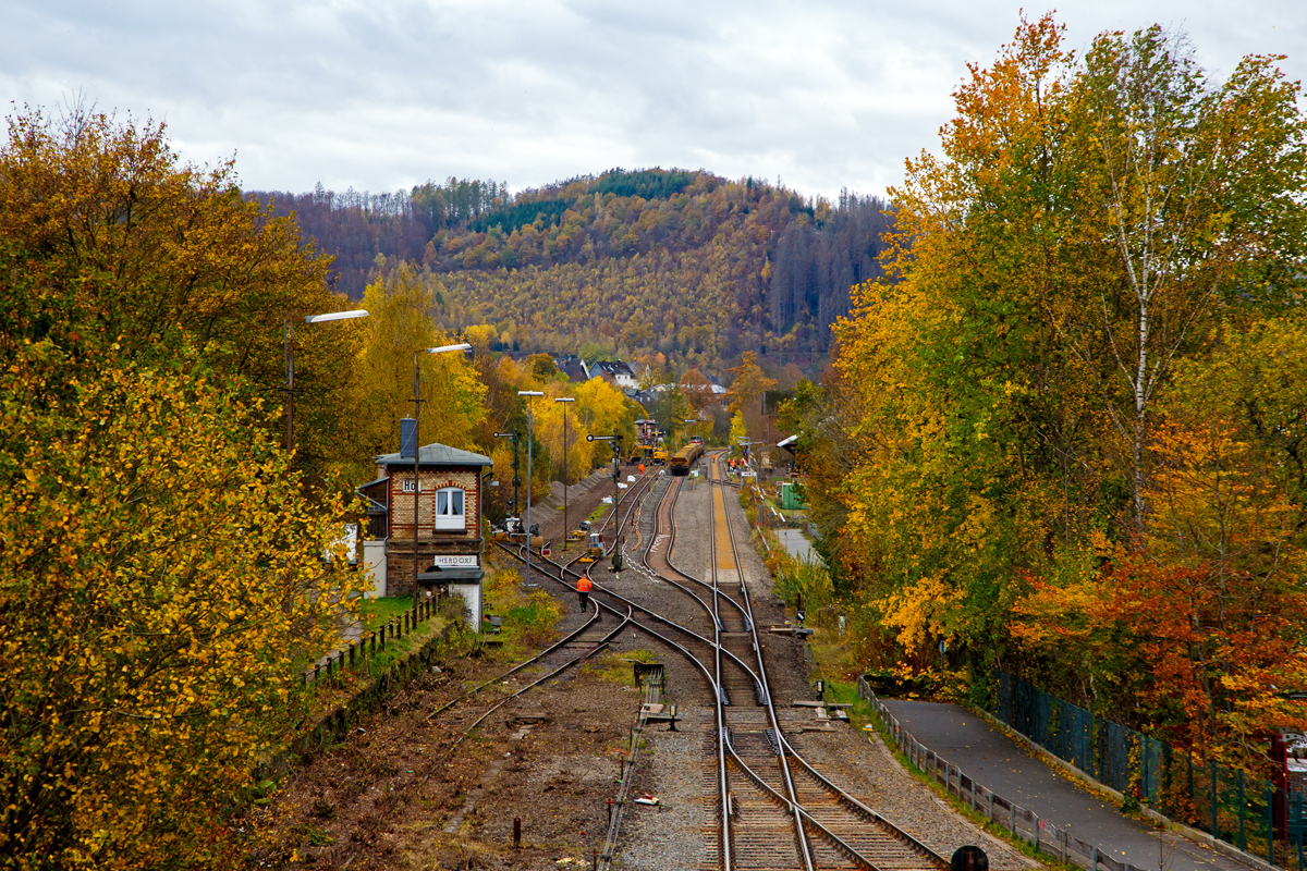 
Blick von der Brücke Wolfsweg („Achenbachs Brücke“) auf den Bahnhof Herdorf am 02.11.2020. Am Sonntag den 01.11.2020 war auf der Baustelle Ruhetag, der Oberbau von Gleis 4 wurde heute Morgen demontiert, nun hat der Aushub vom Schotterbett begonnen. Auf Gleis 2 steht die Vossloh G 12 „Karl August“ 92 80 4120 001-7 D-KAF der KAF Falkenhahn Bau AG mit einem zwei Seiten Kippwagenzug (Kippwagen MK 45 DH „LW-Kipper“, der Gattung Rlps), der mit dem Aushub (Altschotter) beladen wird. 

Der Altschotter wird später zum Recycling nach Bochum gefahren. 

