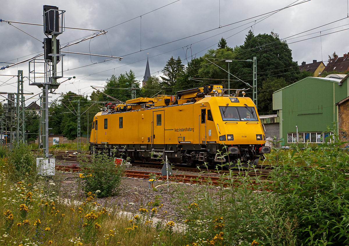 Das Oberleitungsinstandhaltungsfahrzeug 711 201 (99 80 9136 001-1 D-DB) der DB Netz AG, ein Robel 57.44, fhrt am 15.07.2021 durch Betzdorf (Sieg) in Richtung Kln.

Der IFO 57.44 wurde 2009 von der ROBEL Bahnbaumaschinen GmbH in Freilassing unter der Fabriknummer 57.44-001 gebaut und an die DB Netz AG geliefert.

Zur neusten Generation an Fahrzeugen fr die Durchfhrung von Instandhaltungs- und Entstrungsarbeiten an Oberleitungsanlagen gehrt die von der Deutsche Bahn AG bezeichnete Baureihe 711.2, welche von der Firma ROBEL Bahnbaumaschinen GmbH in Freilassing seit 2009 unter der Bezeichnung IFO 57.44 hergestellt wird.

Im Auftrag der DB hatte die Firma Robel mit dem IFO 57.44 ein vierachsiges Fahrzeug fr Reparaturen und Wartung an Oberleitungsanlagen entwickelt, dass auf allen Strecken der DB einsetzbar ist. 

Der Wagenkasten ist zweckmig gestaltet und mit Stahlblech verkleidet. An den Fronten finden sich unter der Verkleidung der Fahrzeugkpfe, die an moderne Elektrolokomotiven angelehnt sind, stabile Schweikonstruktionen zur Aufnahme der bei einem Unfall freiwerdenden Krfte.

Der Antrieb erfolgt durch zwei Dieselmotoren der Bauart TCD 2015 V08 von Deutz mit jeweils 480 kW, die jeweils mittels eines hydraulischen Getriebes (Voith Turbogetriebe T 212 bre),    auf beide Achsen (mit je einem Voith Radsatzgetriebe SK-525) eines Drehgestells wirken. Lassen es die Streckenverhltnisse zu oder kommt es zu Strungen, kann auch mit nur einer Antriebsanlage gefahren werden. Fr die Arbeitsfahrt (bei den Montage- und Wartungsarbeiten) ist an einem Drehgestell ein hydrostatischer Antrieb installiert, der durch einen der beiden Haupt-Dieselmotoren angetrieben wird. Dieser erlaubt eine Fahrt im Geschwindigkeitsbereich von 0 bis 10 km/h. Die Hchstgeschwindigkeit betrgt 140 km/h (Technisch mglich 155 km/h), was vor allem fr die schnelle Beseitigung von Strungen ntig ist. Bei einer Fahrt mit 100  km/h kann das Fahrzeug eine Anhngelast von 150 t befrdern und ist hierzu mit einer Schraubenkupplung ausgerstet.

Das Fahrzeug besitzt zwei Endfhrerstnde mit jeweils zwei Pltzen. ber ein Monitorsystem knnen die Fahrzeuglngsseiten beobachtet werden. Eine weitere Kamera ist auf die Oberleitung und den Mess-Stromabnehmer gerichtet, wobei die Bilder zur spteren Dokumentation aufgezeichnet werden knnen. An die Fhrerstnde schlieen sich Sozial- und Arbeitsrume an. So ist beispielsweise fr lngere Einstze eine vollwertige Kchenzeile mit Khlschrank, Mikrowelle und Kaffeemaschine eingebaut worden. Ebenfalls vorhanden ist eine Nasszelle, deren Abwsser ber einen Bioreaktor aufbereitet und erst dann gereinigt in das Gleis abgegeben werden. Mittelpunkt des Fahrzeugs ist der Arbeits- und Werkstattraum, der von auen ber die beidseitigen 1.510 mm breiten Tren erreichbar ist. Auf beiden Seiten befinden sich ausschwenkbare Hebevorrichtungen fr Lasten bis zu 250 kg. 

Auf dem Dach befinden sich zwei Hubarbeitsbhnen, je eine vom Typ PA 95 und eine vom Typ PA 360 der Firma Palfinger. Die PA 95 ist vorrangig fr Arbeiten am Fahrdraht bis zu einer Hhe von 9 m ber Schienenoberkante gedacht, whrend mit der PA 360 bis zu einer Arbeitshhe von 21 m auch das Kettenwerk und Mastspitzen erreicht werden knnen. Auch ein Absenken der Bhne neben dem Fahrzeug ist mglich, um beispielsweise Gerte und/oder Material aus dem Werkstattwagen direkt in die Bhne umzuladen.

Von diesem modernen Fahrzeug hatte die Deutsche Bahn AG ursprnglich acht Fahrzeuge dieser Bauart bestellt, die bis zum Sommer 2011 ausgeliefert wurden. Sie kommen im gesamten deutschen Streckennetz zum Einsatz und ersetzen die ber 30 Jahre alten Turmtriebwagen der DB-Baureihe 704. Ab Februar 2014 wurden nach einem Folgeauftrag vier weitere Fahrzeuge ausgeliefert.

Das Fahrzeug ist in dieser Ausfhrung speziell fr die Belange der Deutschen Bahn AG konstruiert worden, kann aber bei Bedarf auch fr andere interessierte Bahnunternehmen auf deren spezifische Anforderungen angepasst werden.

TECHNISCHE DATEN:
Hersteller: ROBEL Bahnbaumaschinen GmbH, Freilassing
Spurweite: 1.435 mm (Normalspur)
Achsformel:  B'B'
Lnge ber Puffer:  24.500 mm
Drehzapfenabstand: 17.000 mm
Achsabstand im Drehgestell: 2.500 mm
Eigengewicht:  77 t
Hchstgeschwindigkeit:  140 km/h (Technisch mglich 155 km/h) / geschleppt 120 km/h
Tankinhalt:  2750 l
Leistung: 2 x 480 kW (2 x 652 PS)
Kraftbertragung:  hydrodynamisch (Streckenfahrt) hydrostatisch (Arbeitsfahrt)
Zur Mitfahrt zugel. Personen: 9
Anhngelast: 150 t
Zuladung  5 t
Bremse: KB C-KE-PR-H mZ (D)

Motordaten:
2 Stck Deutz - wassergekhlter-V8-Dieselmotor mit Turboaufladung, Ladeluftkhlung und Vierventiltechnik. Motor in V-Ausfhrung im Winkel von 90, er hat ein elektronisches, ber Magnet-Ventile gesteuertes Einspritzsystem.
Motortyp: TCD 2015 V08
Zylinderzahl: 8
Bohrung/Hub: 132 / 145 mm
Hubvolumen: 15,9 l
Verdichtungsverhltnis: 17,5:1
Nenndrehzahl: 1800 min-1 
Leistung: 480 kW (652 PS)
Max. Drehmoment: 2.890 Nm
Niedrigste Leerlaufdrehzahl:  600 min-1
Motorgewicht: 1.245 kg

Getriebe fr Streckenfahrt (2 Stck):
Voith Turbogetriebe T 212 bre 

Das Turbogetriebe ist ein 3-Gang-Getriebe mit einem Drehmomentwandler, zwei Strmungskupplungen, einer integrierten hydrodynamischen Bremse und mechanischem Wendeteil. Zustzlich ist eine Voith-Federkupplung an das Schwungrad des Dieselmotors angeflanscht.

Bei Traktion erfolgen die Gangwechsel automatisch ohne Zugkraftunterbrechung weich, sto- und verschleifrei durch    Fllen und Entleeren der Kreislufe. Die dynamische Bremse ermglicht verschleifreies Bremsen, kurzzeitig bis 450 kW Bremsleistung.

Die Kraftbertragung vom Turbogetriebe erfolgt ber Gelenkwellen auf Voith Radsatzgetriebe SK-525 (1 Stck/Achse = 4 Stck) und somit auf die Achse.
