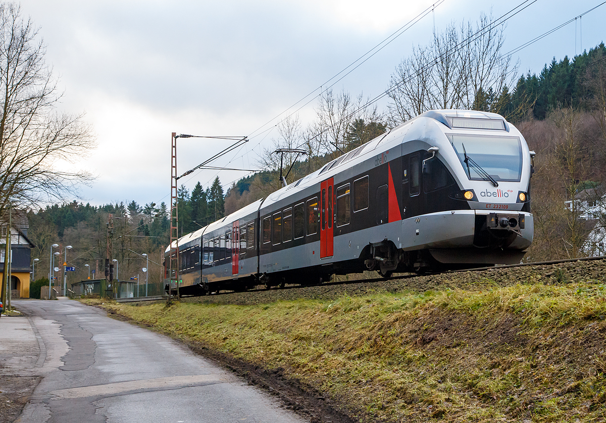 
Der 3-teiligen Stadler Flirt ET 23 2109  Kreis Siegen-Wittgenstein  der Abellio Rail NRW hat am 25.12.2017 gerade den Bf Kirchhundem verlassen und fhrt als RB 91  Ruhr-Sieg-Bahn  (Siegen - Hagen) weiter in Richtung Hagen.

Er befhrt die Ruhr-Sieg-Strecke,  eine 106 Kilometer lange zweigleisige, elektrifizierte Hauptstrecke von Hagen nach Siegen ber Iserlohn-Letmathe, Finnentrop und Kreuztal. Die tunnelreiche Strecke fhrt berwiegend durch das Tal der Lenne und sdlich von Lennestadt-Altenhundem ber die Wasserscheide zwischen Ruhr und Sieg.

Die DB plant ab dem Fahrplanwechsel 2019/2020 im Dezember 2019, eine Intercity-Linie von Frankfurt ber Siegen und Iserlohn-Letmathe nach Mnster einzurichten. Ich persnlich finde das wird auch wieder Zeit, nach Einstellung der Interregio-Linie Frankfurt – Mnster (– teilweise bis Norddeich Mole) im Jahre 1993, und es waren immer gut gefllte Zge. Zudem hoffe ich das die Halte, gegenber der RE 16, ausgednnt werden.  

Leider auch nur ein Zwischenspiel bildete die Schnellzugverbindung (Mo-Fr)  mit dem D 810/811, die Dortmund mit Frankfurt in einer Reisezeit von unter drei Stunden verband, welche unterwegs nur in Siegen-Weidenau und Wetzlar hielt und aus hochwertigen, sonst nur in Intercity-Zgen gefhrten Wagen gebildet war. Diese war schneller als ber Koblenz und entlang des Rheins. Da es von der Findigkeit des Kursbuchlesers abhing, diese primr fr Geschftsreisende konzipierte Verbindung zu ersehen, wurde sie bald wieder eingestellt.