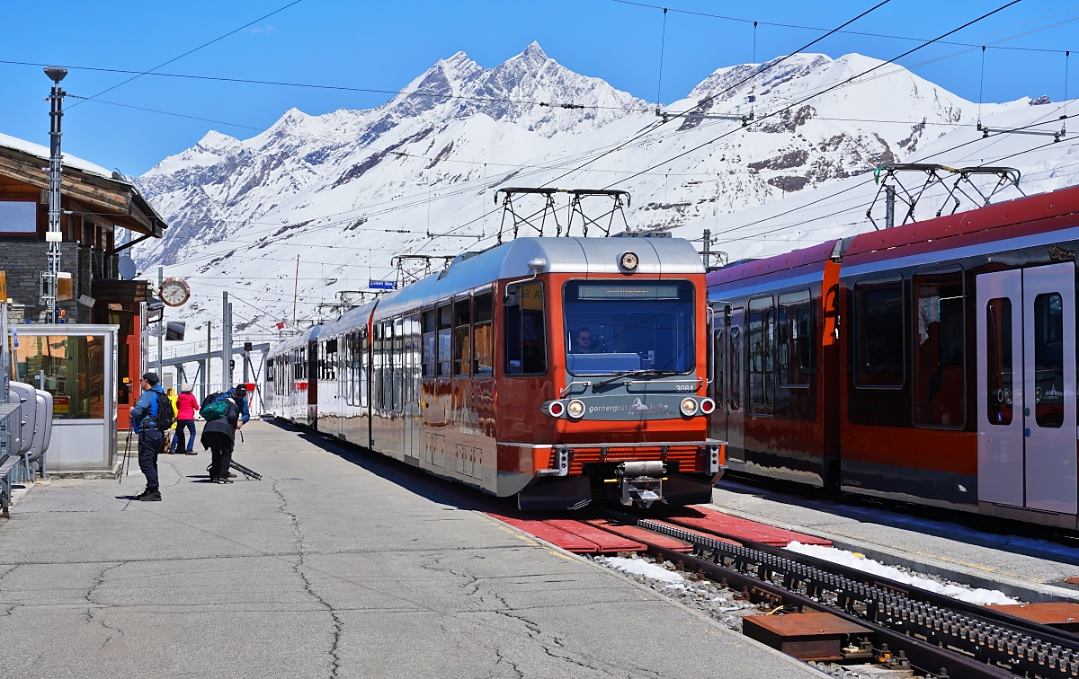 Der Bhe 4/6 3084 und ein weiterer Bhe 4/6 kommen am 10.05.2024 auf der Fahrt zum Gornergrat in der Station Riffelberg an, daneben die beiden Triebwagen Bhe 4/6 3094 und 3095 auf der Talfahrt 