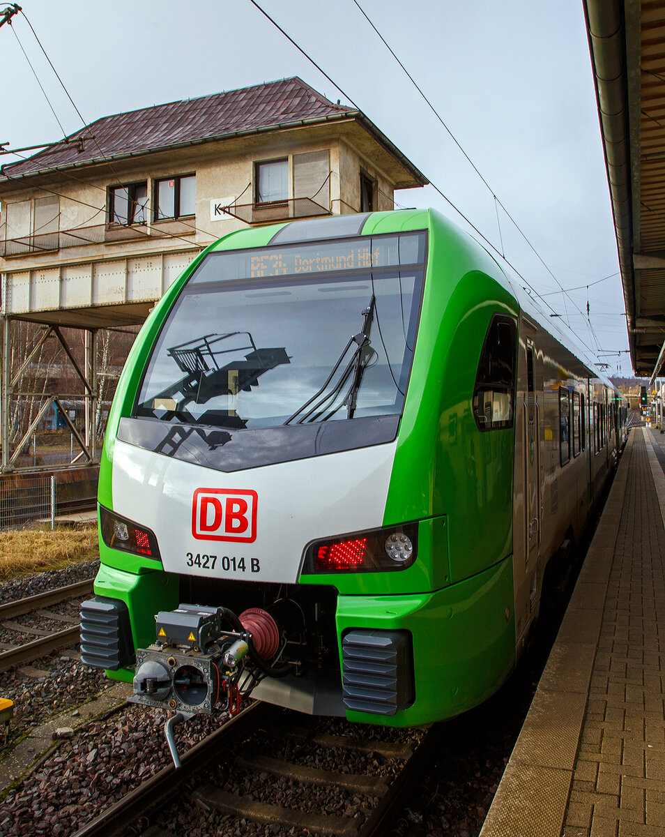 Der für die DB Regio AG – NRW fahrende dreiteilige Stadler FLIRT 3 XL 3427 014 (94 80 3427 014-0 D-STAP / 94 80 3827 014-6 D-STAP / 94 80 3427 514-9 D-STAP) der ZV VRR Eigenbetrieb Fahrzeuge und Infrastruktur, am 15.12.2022, als RE 34 „Dortmund-Siegerland-Express“ (Siegen - Letmathe - Dortmund), beim Halt im Bahnhof Kreuztal. Links das ehem. Reiterstellwerk Kreuztal Nord (Kn).

Der Stadler FLIRT 3 XL wurde 2020 von der Stadler Pankow GmbH in Berlin unter den Fabriknummern 42354 bis 42356 gebaut und an den Zweckverband Verkehrsverbund Rhein-Ruhr Eigenbetrieb Fahrzeuge und Infrastruktur geliefert. Eigentlich war dieser FLIRT 3 XL wie 9 weitere für die Bedienung der Regiobahnstrecke S 28 Kaarst - Neuss - Düsseldorf - Mettmann - Wuppertal vorgesehen, wo die Elektrifizierung bis 2020 erfolgen sollte. Da aufgrund von Verzögerungen der elektrische Betrieb voraussichtlich erst 2026 aufgenommen werden kann, wurden die inzwischen gelieferten Triebwagen u. a. von der DB Regio AG NRW eingesetzt.

Stadler FLIRT 3 XL, dreiteilig der BR 3427:
Die Fahrzeuge der BR 3427 vom Typ STADLER Flirt 3 XL sind, in der sogenannten XL-Ausführung, mit 67.600 mm um 4,4m länger als die normalen STADLER Flirt 3 (BR 1427), zudem haben diese 6 Türen pro Fahrzeugseite (anstatt 3). Der FLIRT verfügt über eine hohe Antriebsleistung (2.720 kW) und eine maximale Geschwindigkeit von 160 km/h. Die 3-Teiler haben 180 Sitzplätze (16 in der 1.Klasse und 154 in der 2. Klasse).

Der VRR Auftrag umfasste die Lieferung von 41 Triebzügen des Typs FLIRT. Die Bestellung teilte sich auf in 17 dreiteilige und 24 fünfteilige Fahrzeuge. Beide Fahrzeugvarianten verfügen über längere Wagenkästen, der sogenannten XL-Ausführung (FLIRT 3 XL). Ergänzend wird Stadler auch die Instandhaltung der Fahrzeuge in den kommenden 30 Jahren verantworten. Die Fahrzeuge kommen auf den Strecken des S-Bahn-Netzes Rhein-Ruhr zum Einsatz. Der FLIRT verfügt über eine hohe Antriebsleistung und eine maximale Geschwindigkeit von 160 km/h. Der helle, freundliche Fahrgastbereich ist barrierefrei und bietet dem Betreiber individuelle Gestaltungsmöglichkeiten. Sie verfügen über bequemere Sitze, überwiegend in 4er-Sitzgruppen mit Vis-à-vis-Anordnung, Toiletten sowie Steckdosen zum Aufladen von Smartphones, Tablets oder Rechnern.

Technik:
• Ausgelegt für die Verbandsfahrt von bis zu 3 Fahrzeugen
• Automatische Mittelpufferkupplungen (Scharfenbergkupplung)
• Leichtbauweise aus Aluminium
• Redundante Antriebsausrüstung bestehend aus 2 Antriebssträngen mit je einem Transformator, IGBT-Stromrichter und 2 Asynchronfahrmotoren
• Luftgefederte Fahrwerke sorgen für die erforderliche Laufruhe
• Die Fahrzeuge wurden in zwei unterschiedlichen Designs ausgeliefert (S-Bahn Rhein-Ruhr Design [grün/weß] sowie Regiobahn Design [rot/weiß])

Komfort:
• Klare Trennung von Mehrzweckbereichen für den Fahrradtransport sowie für die Beförderung von Rollstuhlfahrern
• 12 Fahrradstellplätze
• 2 extrabreite zweiflügelige Schwenkschiebetüren je Wagenkasten
• Klimatisierter Fahrgastraum und Fahrerraum
• 1 geschlossenes WC-System je EMU3 bzw. 2 geschlossene WC-Systeme je EMU5
• Einstiegshöhe 780 mm
• Modernes Fahrgastinformationssystem
• Passagier-WLAN im ganzen Fahrgastraum

TECHNISCHE DATEN (BR 3427 - Stadler FLIRT 3 XL, dreiteilig):
Spurweite: 1.435 mm (Normalspur)
Achsanordnung: Bo' 2' 2' Bo'
Länge über Kupplung: 67.600 mm
Fahrzeugbreite: 2.820 mm
Fahrzeughöhe: 4.270 mm
Fußbodenhöhe Niederflur: 780 mm
Fußbodenhöhe Hochflur: 1.150 mm
Einstiegsbreite: 1.800 mm je Tür 
Anzahl der Türen je Fahrzeugseite: 6
Sitzplätze: 180 (1. Klasse 16 / 2. Klasse 164)
Stehplätze (4 Pers./m²): 260
Dienstgewicht: 
Achsabstand im Drehgestell: 2.700 mm
Lauf- und Triebraddurchmesser: 870 mm (neu)
Höchstgeschwindigkeit: 160 km/h
Max. Leistung am Rad: 2.720 kW
Dauerleistung am Rad: 2.000 kW
Max. Anfahrbeschleunigun: 1,2 m/s²
Kupplung: Scharfenbergkupplung (Schaku) Typ 10

Quellen: Stadler Rail