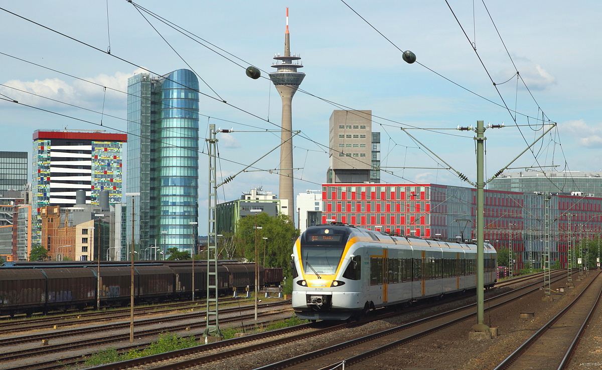 Der Stadler Flirt ET 7.01 der Eurobahn durchf�hrt als RE 13 Hamm - Venlo/NL (Maas-Wupper-Express) am 25.05.2014 D�sseldorf-Hamm. Im Hintergrund die in den letzten Jahren enstandene D�sseldorfer Hafen-City, der der Triebwagen einen weiteren Farbtupfer hinzuf�gt.