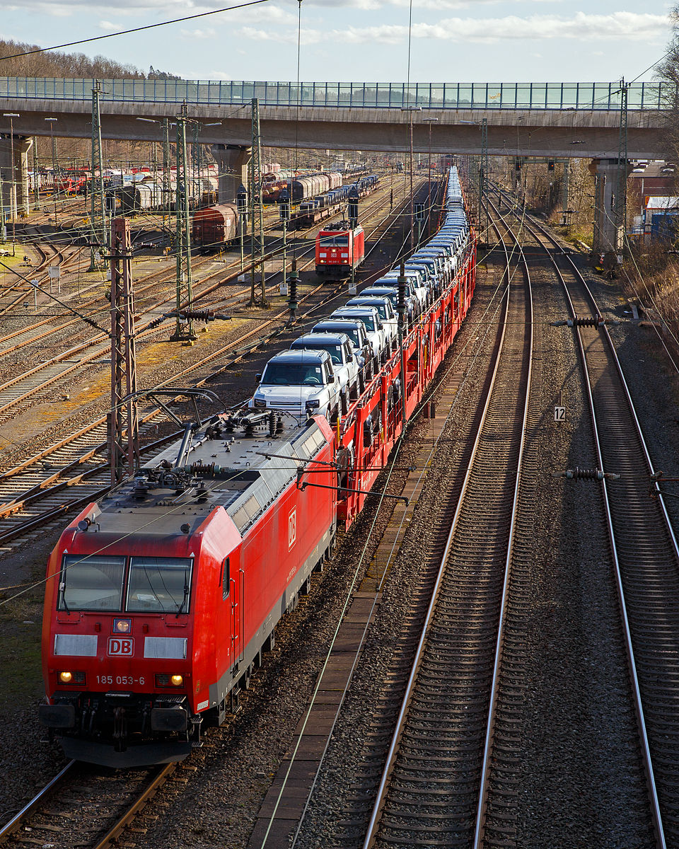 Die 185 053-6 (91 80 6185 053-6 D-DB) der DB Cargo AG, hat am 23.02.2022, mit einem sehr langen Autotransportzug, beim Rbf Kreuztal Hp 0. Der Güterbahnverkehr in Richtung Hagen staute sich etwas in Kreuztal, da die Ruhr-Sieg-Strecke entlang der Lenne (durchs Sauerland) an diesem Tag nur eingleisig befahrbar war. Links der Rangierbahnhof (Rbf) Kreuztal, wo auch u.a. noch die 185 248-2 steht.

Die Wagen von dem Autotransportzug waren Doppelstock-Autotransportwagen der Gattung Laaeffrs 561 (25 80 4382 xxx-x D-ATG) der DB Cargo Logistics GmbH (ex ATG Autotransportlogistic GmbH). 

Die TRAXX F140 AC1 wurde 2002 von Bombardier Transportation GmbH in Kassel unter der Fabriknummer 33461 gebaut.
