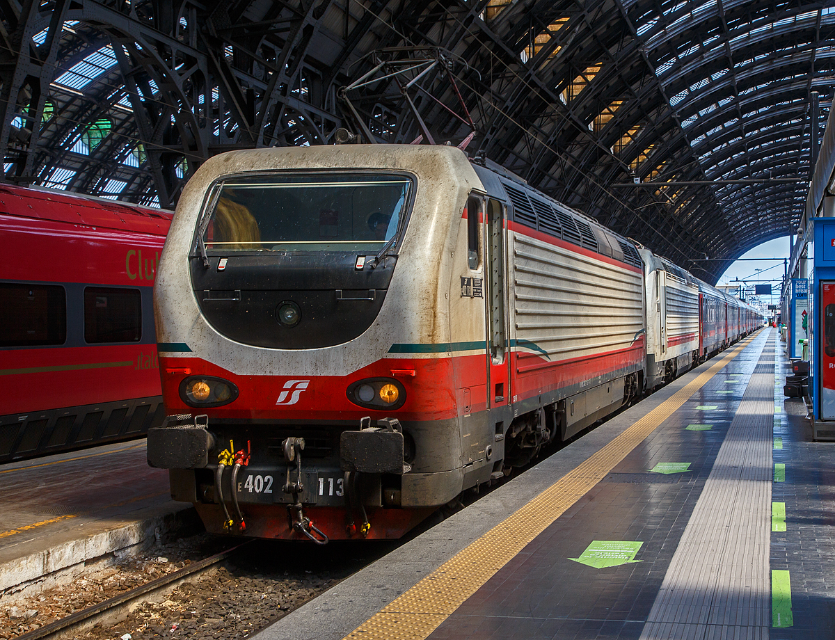 Die beiden E.402B 113 und 111 (91 83 2402 113-x I-TI und 91 83 2402 111-5 I-TI) erreichen am 12.07.2022, mit einem Trenitalia InterCity Notte (ICN), den Bahnhof Milano Centrale (Mailand Hbf).

Die FS E.402B ist eine Weiterentwicklung der E.402A, verfügt jedoch gegenüber ihrem Vorgängermodell zum Beispiel über ein höheres Gewicht sowie einen neu gestalteten und futuristischeren Wagenkasten. Die Höchstgeschwindigkeit ist jedoch mit 200 km/h etwas geringer als bei der E.402A (mit 220 km/h). Von den Loks wurden 80 Stück zwischen 1997 und 2000 von Ansaldo, Firema Trasporti (Fiore-Casertane), ITIN und SOFER gebaut.

Die Baureihe E.402B ist eine Mehrstromlokomotive, sie kann unter 3.000 V Gleichstromspannung, dem hauptsächlichen italienischen Bahnnetz, aber auch auf den italienischen Schnellfahrstrecken mit 25 kV, 50 Hz Wechselstrom fahren. Fernerhin kann sie unter 1.500 V Gleichstrom betrieben werden, dann hat sie aber nur die halbe Leistung. 

Die Lok ist eine vollelektronische Chopperlokomotive, das heißt, wenn die Lokomotiven unter 3.000 V DC fährt, wird der Strom mit Hilfe eines Zerhackers in Wechselstrom umändern, der dann schließlich die Motoren antreibt. 

TECHNISCHE DATEN:
Spurweite:  1435 mm (Normalspur)
Achsformel: Bo'Bo'
Länge: 19.420 mm
Drehzapfenabstand: 10.450 mm
Achsabstand im Drehgestell: 2.850 mm
Treibraddurchmesser:  1.250 mm
Dienstgewicht: 89 t
Höchstgeschwindigkeit: 200 km/h
Stundenleistung: 6.000 kW
Dauerleistung: 5.600 kW
Anfahrzugkraft: 280 kN
Stromsysteme: 3000 V DC, 25 kV - 50 Hz AC und 1500 V DC (bei halber Leistung)