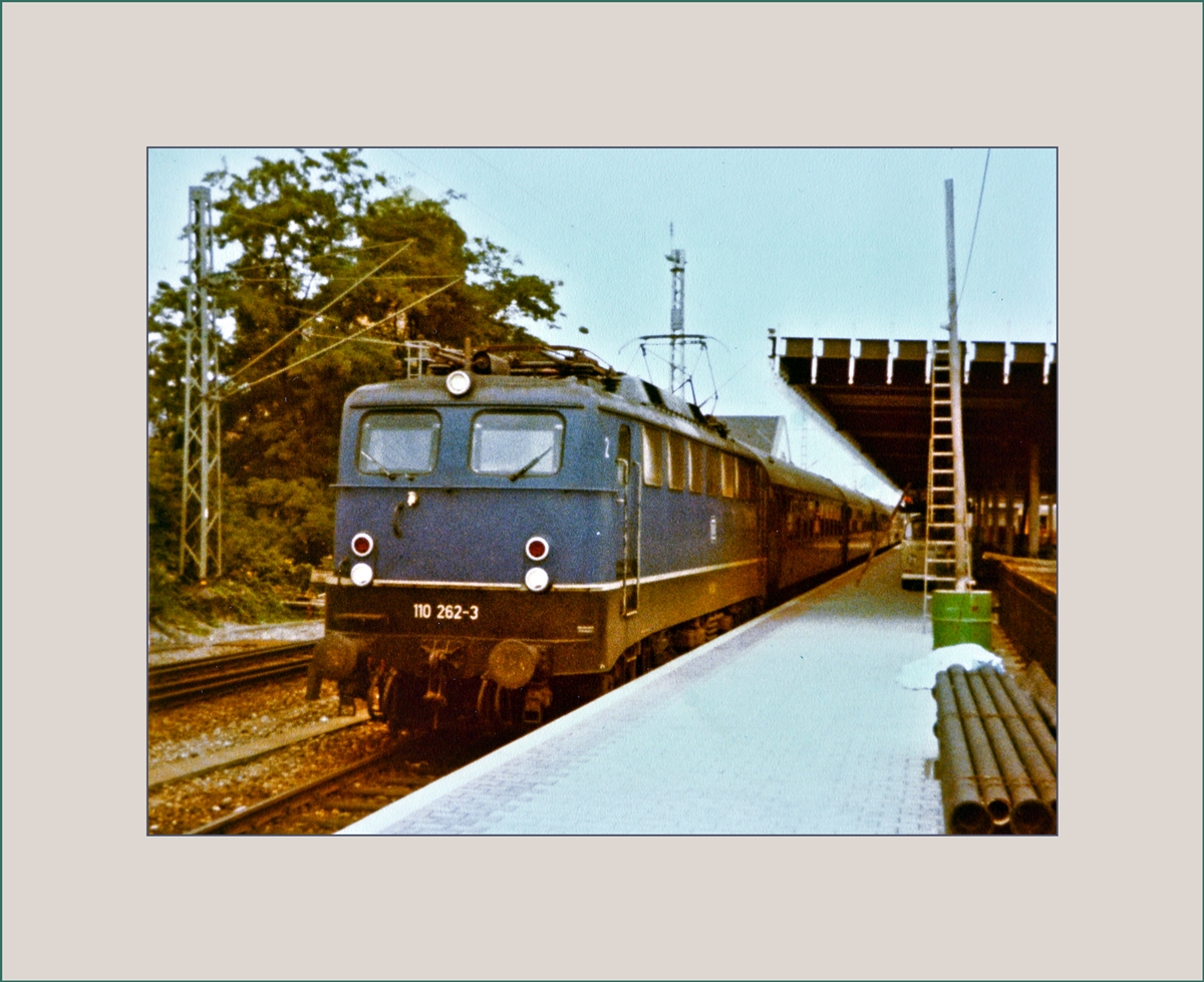 Die DB 110 262-5 mit dem D 358 von Berlin nach Basel SBB, welcher auch einen direkten Schlafwagen aus Moskau führt beim Halt in Basel Bad. Bf. 
Das neue Bahnsteigdach ist im Moment der Aufnahme noch im Bau. 

30. Juli 1982