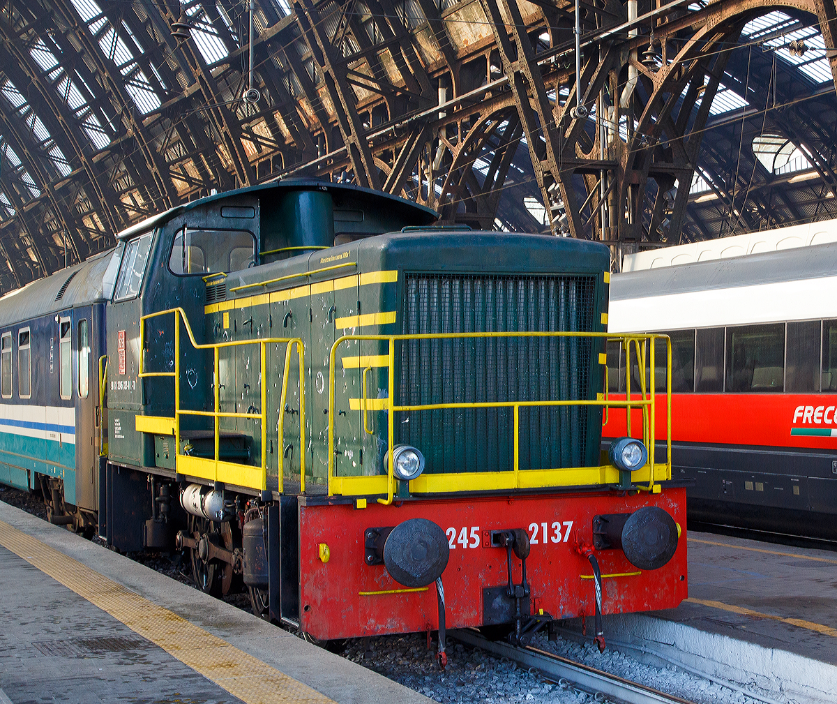 
Die Dieselrangierlok D.245.337-0 (98 83 2245 337-0 I-TI) der Trenitalia (100-prozentige Tochtergesellschaft der FS), ex FS 245.2137, hängt im Bahnhof Milano Centrale am 29.12.2015 einen Zug mit IC-Wagen an.

Die FS (Ferrovie dello Stato Italiane S.p.A. / Italienische Staatseisenbahnen AG) führte 1963 die Reihe D.245 als leistungsfähigste Rangierlok ein. Die dreiachsigen Kraftpakete (Achsfolge C) wurden von verschiedenen Firmen in unterschiedlichen Formen geliefert. 

Die Formen ergeben sich aus den unterschiedlichen Serien, Herstellern und Baujahren und sind wie folgt:
245.6001–6124, Baujahre 1963 bis 1969, Cantieri Navali Riuniti/OM/Jenbacher Werke
245.0001–0058, Baujahre 1964 bis 1968, Hersteller: Antonio Badoni/OM
245.1001–1020, Baujahre 1964 bis 1968, Hersteller: OM/FIAT-Mercedes-Benz
245.2001–2020, Baujahr 1966, Hersteller: Officine Meccaniche Reggiane/Breda
245.2101–2286, Baujahre 1976 bis 1987, Hersteller: Breda/Antonio Badoni/Greco/Ferrosud/IMMER
245.8001–8003, Baujahre 1958 bis 1962, dies waren später von der FS von einem Unternehmen erworben drei Lokomotiven vom Typ Jung R42C, die später zur Hafenbahn Genua kamen. 

Die hier gezeigte Lok 245.2137 wurde 1979 von I.ME.R  S.p.a. in Carini gebaut. Die Serie 245.2101–2286 ist optisch baugleich mit der Serie 245.20 aus dem Jahr 1966, nur geringe Modifikationen wurden vorgenommen und die Kuppelstangen-Lager wurden als Rollenlager ausgeführt, anstelle der Gleitlager.
                                                                                                                                                                                                                    
Sie hat ein hydraulisches Getriebe und Stangenantrieb. Die Achsen werden mittels Kuppelstangen von einer Blindwelle (zwischen der 2. Und 3. Achse) angetrieben. Die Lok hat einen, von 440 auf 370 kW, gedrosselten 12-Zylinderdieselmotor vom Typ Breda ID36, der die Leistung auf das Voith Strömungsgetriebe (hydrostatisch), vom Typ L24. Die Dauerabtriebsleistung beträgt 275 kW. Die Kraftübertragung erfolgt über eine zwischen dem 2. und 3. Radsatz liegenden Blindwelle, Blindwellenkurbeln an den beiden Blindwellenenden und Kuppelstangen auf die Räder der Lok.
 
Technische Daten:
Spurweite:  1.435 mm (Normalspur)
Achsformel:  C
Länge über Puffer: 9.240 mm
Achsabstände:  1.500 / 2.500 mm
Eigengewicht:  46 t
Höchstgeschwindigkeit:  64 km/h (im Rangiergang 32 km/h)
Motorleistung:  370 kW
Dauerleistung:  275 kW
Treibraddurchmesser:  1.040 mm