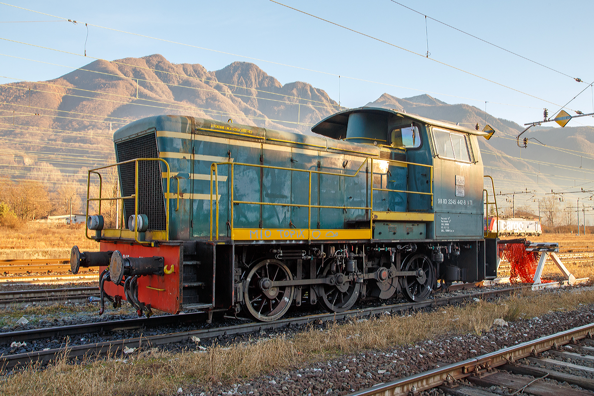 
Die Dieselrangierlok D.245.442-8 (98 83 2245 442-8 I-TI) der Trenitalia (100-prozentige Tochtergesellschaft der FS), ex FS 245.2242, abgestellt am 27.12.2015 im Bahnhofsareal in Domodossola.

Die FS (Ferrovie dello Stato Italiane S.p.A. / Italienische Staatseisenbahnen AG) führte 1963 die Reihe D.245 als leistungsfähigste Rangierlok ein. Die dreiachsigen Kraftpakete (Achsfolge C) wurden von verschiedenen Firmen in unterschiedlichen Formen geliefert. 

Die Formen ergeben sich aus den unterschiedlichen Serien, Herstellern und Baujahren und sind wie folgt:
245.6001–6124, Baujahre 1963 bis 1969, Cantieri Navali Riuniti/OM/Jenbacher Werke
245.0001–0058, Baujahre 1964 bis 1968, Hersteller: Antonio Badoni/OM
245.1001–1020, Baujahre 1964 bis 1968, Hersteller: OM/FIAT-Mercedes-Benz
245.2001–2020, Baujahr 1966, Hersteller: Officine Meccaniche Reggiane/Breda
245.2101–2286, Baujahre 1976 bis 1987, Hersteller: Breda/Antonio Badoni/Greco/Ferrosud/IMMER
245.8001–8003, Baujahre 1958 bis 1962, dies waren später von der FS von einem Unternehmen erworben drei Lokomotiven vom Typ Jung R42C, die später zur Hafenbahn Genua kamen. 

Die hier gezeigte Lok 245.2242 wurde 1984 von Breda und Greco gebaut. Die Serie 245.2101–2286 ist optisch baugleich mit der Serie 245.20 aus dem Jahr 1966, nur geringe Modifikationen wurden vorgenommen und die Kuppelstangen-Lager wurden als Rollenlager ausgeführt, anstelle der Gleitlager.
                                                                                                                                                                                                                    
Sie hat ein hydraulisches Getriebe und Stangenantrieb. Die Achsen werden mittels Kuppelstangen von einer Blindwelle (zwischen der 2. Und 3. Achse) angetrieben. Die Lok hat einen, von 440 auf 370 kW, gedrosselten 12-Zylinderdieselmotor vom Typ Breda ID36, der die Leistung auf das Voith Strömungsgetriebe (hydrostatisch), vom Typ L24. Die Dauerabtriebsleistung beträgt 275 kW. Die Kraftübertragung erfolgt über eine zwischen dem 2. und 3. Radsatz liegenden Blindwelle, Blindwellenkurbeln an den beiden Blindwellenenden und Kuppelstangen auf die Räder der Lok.
 
Technische Daten:
Spurweite:  1.435 mm (Normalspur)
Achsformel:  C
Länge über Puffer: 9.240 mm
Achsabstände:  1.500 / 2.500 mm
Eigengewicht:  46 t
Höchstgeschwindigkeit:  64 km/h (im Rangiergang 32 km/h)
Motorleistung:  370 kW
Dauerleistung:  275 kW
Treibraddurchmesser:  1.040 mm