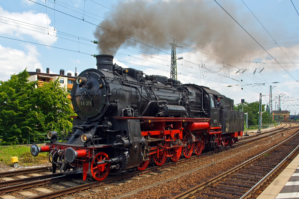 Die Dreizylinder-Güterzug-Dampflokomotive 58 311 der UEF Ulmer Eisenbahnfreunde (ex DR 58 1111-2, ex DR 58 311, ex G 12 Baden 1125), fährt sie am 31.05.2014 beim Dampfspektakel 2014 in den Hauptbahnhof Neustadt an der Weinstraße ein, um einen Personenzug anzuhängen. Sie hat die NVR-Nummer  90 80 0058 311-6 D-UEF.

Die Lokomotive 58 311 wurde 1921 von der Maschinenbaugesellschaft Karlsruhe unter der Fabriknummer 2153 als Baden 1125 (badische  G12) gebaut. Bis 1942 war sie hauptsächlich im BW Karlsruhe Rbf stationiert, kam aber dann, mit zusätzlichem Frostschutz versehen, zum Kriegseinsatz nach Oberschlesien beim BW Groschowitz. Nach einigen Irrfahrten wurde die Lok 1946 in Senftenberg wieder in Betrieb genommen und im BW Reichenbach/Vogtland einer  Gesundungs-L0  unterzogen, mit der die ärgsten Unterhaltungsmängel behoben wurden.

Nach Gastspielen in Werdau, Zwickau, Gera und Greiz kam die Lok 1960 zum BW Karl-Marx-Stadt/Hilbertsdorf, wo sie bis 1973 eingesetzt war. Die letzte Stationierung der inzwischen als 58 1111-2 umgezeichneten Lokomotive war bis 1977 das BW Aue.

Am 19.03.1977 wurde 58 311 ausgemustert, sie fuhr noch als Zuglok eines Güterzuges die damalige deutsch-deutsche Grenze, um anschließend als Lz-Fahrt zum Dampflokmuseum (DDM) in Neuenmarkt-Wirsberg, die sie gekauft hatten. Hier war sie bis zum Verkauf an die UEF im Jahre 1984 als nicht-betriebsfähiges Ausstellungsstück zu sehen.

Nach erfolgter Hauptuntersuchung konnte die Lok am 8. Juni 1985 bereits wieder zugelassen werden und kam bei den Fahrzeugparaden der DB zum 150-jährigen Jubiläum erstmals wieder vor großem Publikum zum Einsatz. Im Winter 1992/93 stand die Lok zur Fahrwerks-Hauptuntersuchung an, die im RAW Meiningen durchgeführt wurde. Seitdem war 58 311 bis zum Ablauf der Kesselfrist im Januar 2001 bei zahlreichen Sonderfahrten in ganz Deutschland, Frankreich und der Schweiz im Einsatz zu bewundern.

Seit 3. Juni 2006 ist diese Lokomotive nach langer und 
aufwändiger Hauptuntersuchung wieder betriebsbereit.

Von dieser Lokbaureihe wurden insgesamt 1478 Loks für verschiedene Bahngesellschaften gebaut.
Die Deutsche Bundesbahn musterte ihre Exemplare bereits 1953 aus. Die Deutsche Reichsbahn hatte 1968 noch 300 Maschinen im Einsatz. Bei Einführung der EDV-Nummern im Jahr 1970 wurde bei den dreistelligen Betriebsnummern im Allgemeinen eine eins an der Tausenderstelle eingefügt. Die letzten Lokomotiven wurden Ende der 1970ger-Jahre ausgemustert. 

Die gedrungene, bullig wirkende Güterzuglokomotive erreichte zwar nur eine Höchstgeschwindigkeit von 65 km/h, mit ihrem Dreizylindertriebwerk verfügte sie aber übergenügend Leistung (1.540 PS) für schwere Güterzüge im Bergland.



Technische Daten der 58 311:
Bauart:  1'E h3
Gattung:  G 56.16 (5 von 6 Achsen angetrieben / 16 t Achslast)
Spurweite:  1435 mm (Normalspur)
Länge über Puffer:  18.495 mm
Dienstgewicht:  93,6 t (ohne Tender)
Achslast:  16,3 t
Höchstgeschwindigkeit:  65 km/h
Indizierte Leistung:  1.133 kW/ 1.540 PSI
Treibraddurchmesser:  1.400 mm
Laufraddurchmesser vorn:  1.000 mm
Zylinderanzahl:  3
Zylinderdurchmesser:  570 mm
Kolbenhub:  660 mm
Kesselüberdruck:  14 bar
Tender:  pr. 3 T 20
Wasservorrat:  20,0 m³
Kohlevorrat: 6 t