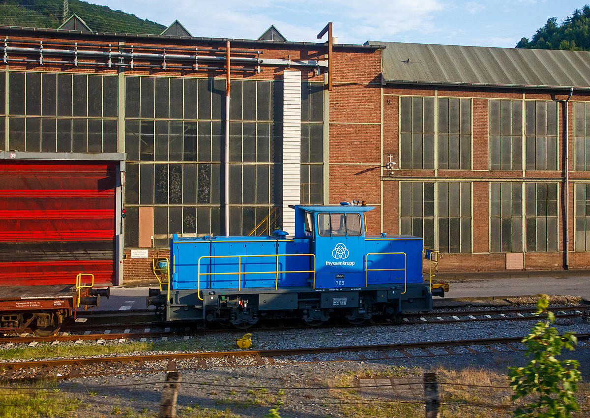 Die Lok 763 der thyssenkrupp Hohenlimburg GmbH, ex 763 Hoesch Hohenlimburg GmbH, ex SK 32 (Siegener Kreisbahn GmbH), am 31.05.2022 auf dem Werksgelnde in Hagen-Hohenlimburg, aus einem fahrenden Zug heraus fotografiert.

Die Lok ist eine MaK G 763 C, sie wurde 1990 von der Maschinenbau Kiel GmbH (MaK) unter der Fabriknummer 700099 gebaut und an die damalige Siegener Kreisbahn GmbH als SK 32 geliefert. Zum 23.12.2004 nach der Umbenennung zur Kreisbahn Siegen-Wittgenstein GmbH wurde sie zur KSW 32 und war von 2005 bis 2007 an die MEG - Mrkische Eisenbahn-Gesellschaft mbH in Ldenscheid vermietet. Im Dezember 2007 ging sie ber Vossloh Locomotives an die Hoesch Hohenlimburg GmbH als Lok 763, zum 01.07.2016 wurde Hoesch von thyssenkrupp bernommen.
