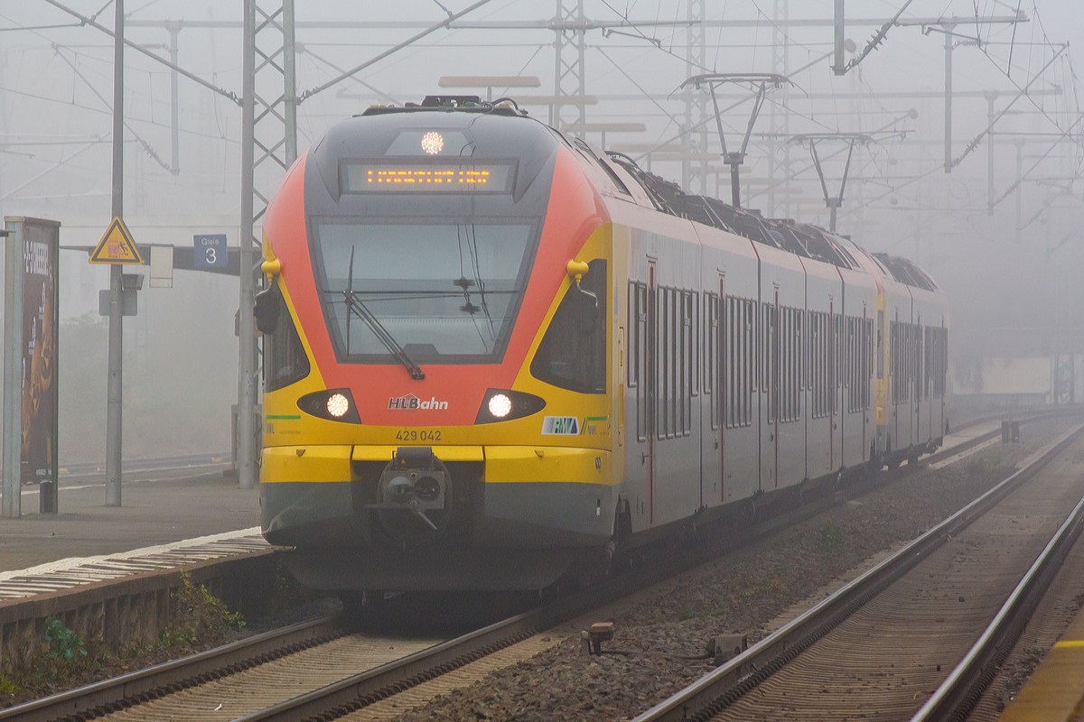 
Durch den Nebel in der Wetterau....
Der 5-teilige Stadler Flirt 429 042 / 542 gekoppelt mit dem 3-teiligen Stadler Flirt 427 543 / 427 043 der HLB Bahn (Hessischen Landesbahn) fahren am 01.11.2014, als RE 99 / RE 40 Siegen - Gießen - Frankfurt Hbf (Umlauf HLB24957), durch den Bahnhof Butzbach in Richtung Frankfurt am Main. 
Die Linie verkehrt in NRW als RE 99 und im Gebiet des Rhein-Main-Verkehrsverbundes in Hessen als RE 40.