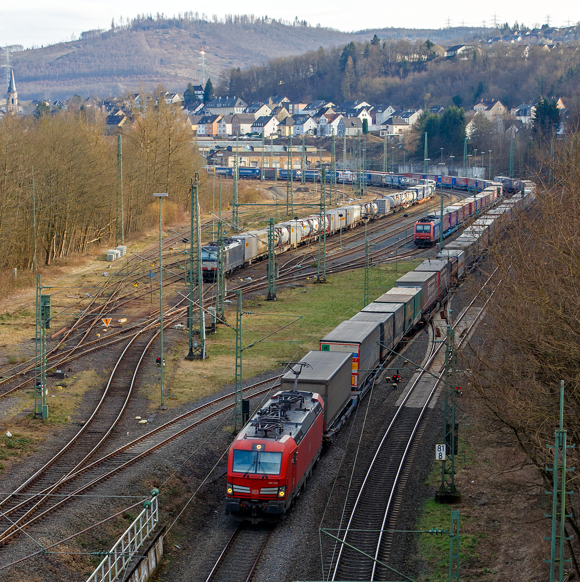 Durch die Sperrung der rechten Rheinstrecke bei Bonn-Beul ist die Woche wieder viel Umleiterverkehr auf der Siegstrecke....
Hier am 12.03.2022 ein Blick von der Brücke in Betzdorf-Bruche auf den Rangierbahnhof Betzdorf/Sieg und die Siegstrecke. Rechts auf der Siegstrecke fährt die 193 313 (91 80 6193 313-4 D-DB), eine Siemens Vectron MS, der DB Cargo AG mit einem KLV-Zug in Richtung Köln. Während im Rbf links die an die DB Cargo vermietete Siemens Vectron MS der MRCE Dispolok, die X 4 E – 701 / 193 701-0 (91 80 6193 701-0 D-DISPO) mit einem Container-/KLV-Zug und rechts davon die SBB Cargo AG Re 482 007-2 (91 85 4482 007-2 CH-SBBC) mit einem „Winner“-KLV-Zug abgestellt sind. 

Die DB Cargo 193 313 eine Vectron MS wurde 2018 von Siemens in München-Allach unter der Fabriknummer 22414 gebaut und an die DB Cargo geliefert. Diese Vectron Lokomotive ist als MS – Lokomotive (Multisystem-Variante) mit 6.400 kW konzipiert und zugelassen für Deutschland, Österreich, Schweiz, Italien und Niederlande (D/A/CH/I/NL), sie hat eine Höchstgeschwindigkeit von 200 km/h. So ist es möglich ohne Lokwechsel vom Mittelmeer die Nordseehäfen Rotterdam oder Hamburg an zu fahren.