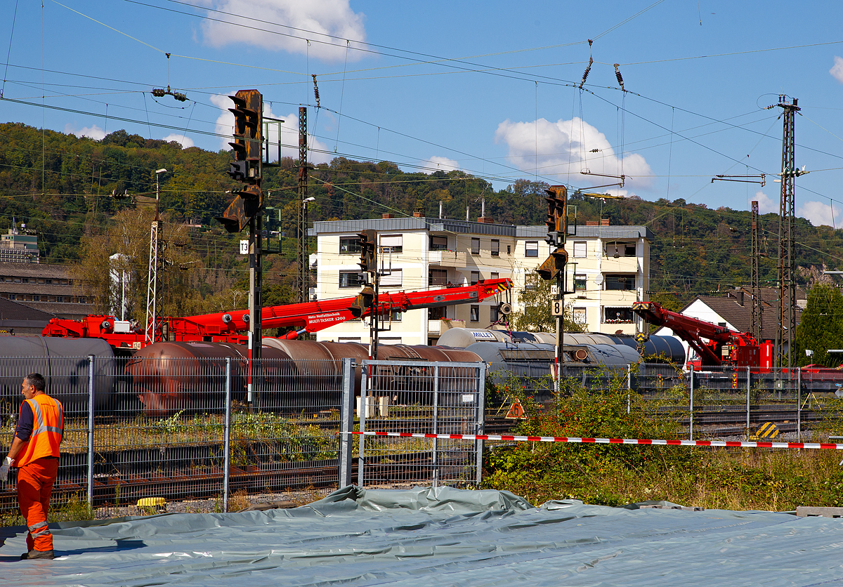 
Es gibt noch viel zu tun in Niederlahnstein (hier am 02.09.2020). Drei Krane der DB Netz Notfalltechnik sind im Einsatz.

Hier im Einsatz sind, links der 120 t-Kran 732 003 (D-DB 99 80 9471 003-0) ein Kirow MULTI TASKER KRC 1200 und rechts der 100 t-Kran 733 001 „Bulldog“ ein Kirow MULTI TASKER KRC 910.

Gegen 18.40 Uhr am Sonntagabend des 30.08.2020 Mitten im Bahnhof kommt es zum Unglck: Ein Gterzug entgleist aus bislang noch unbekannten Ursachen, mehrere Kesselwagen waren aus den Gleisen gesprungen und umgekippt. Verletzte gab es glcklicherweise keine. Doch jetzt droht eine Katastrophe, der Gterzug hatte Diesel geladen. Der Gterzug war auf der Fahrt von Rotterdam nach Basel.

Fnf Kesselwagen waren umgekippt, bis zu 150.000 Liter Diesel sollen ausgelaufen und ins Erdreich gelangt sein. Von den insgesamt acht beschdigten Kesselwagen seien zwei komplett ausgelaufen.

Die Strecke zwischen Koblenz und Bad Ems wurde sofort gesperrt, dies betrifft auch die rechte Rheinstrecke. Die Aufrumarbeiten werden vermutlich 2 Wochen dauern.
