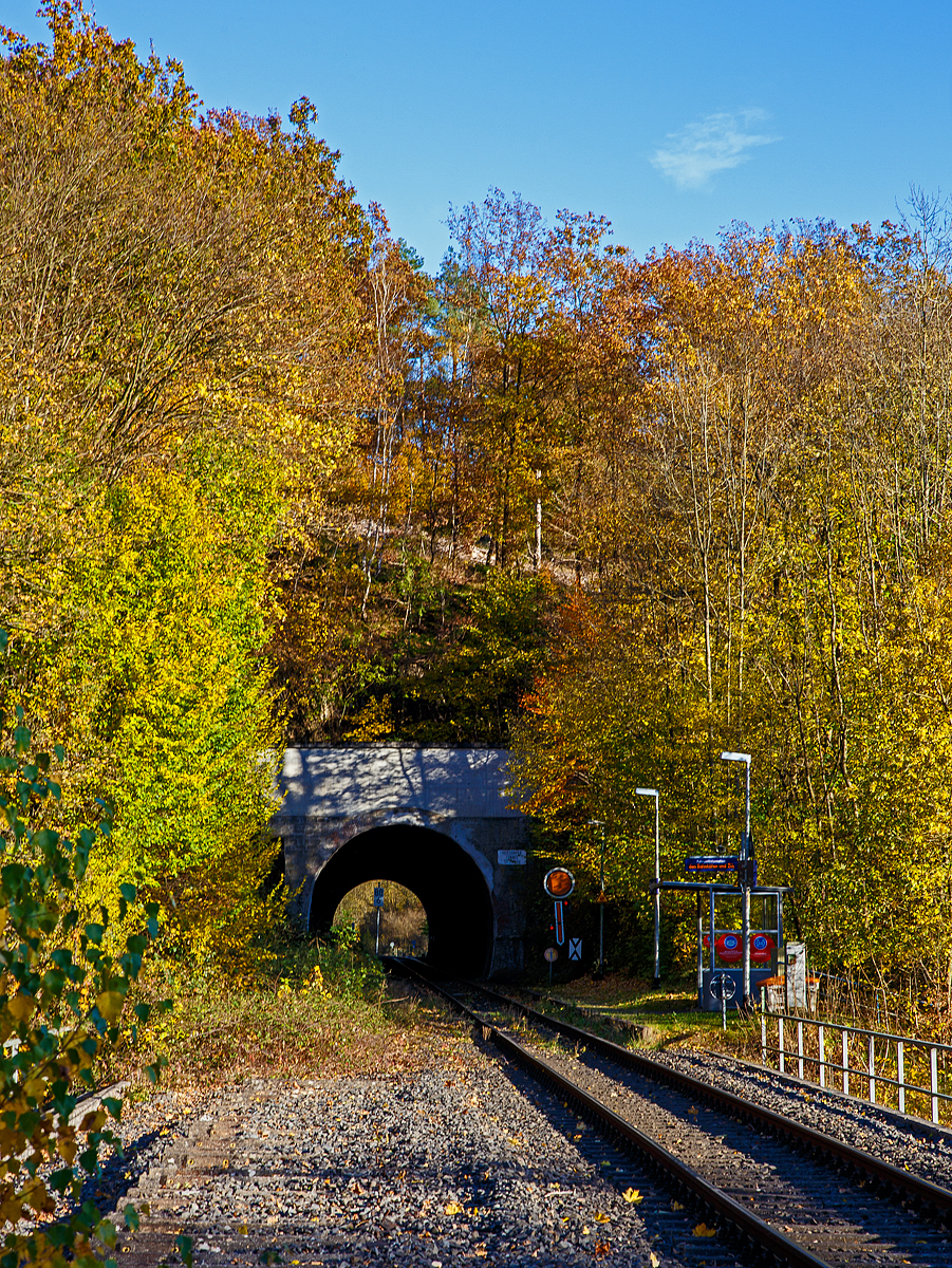 Herbstzeit im Hellertal.....
Der Bedarfs-Haltepunkt Herdorf-Königsstollen dahinter der Herdorfer Tunnel (137 m lang) bei km 88,6 der Hellertalbahn - KBS 462 (Bahnstrecke Köln-Deutz – Betzdorf – Herdorf – Haiger – Gießen). Vorm Tunnel das (Form) Vorsignal für das Einfahrtsignal vom Bahnhof. Es zeigt Vr 0 „Halt erwarten“ (Die runde Scheibe steht senkrecht, der Flügel zeigt er senkrecht nach unten). 

Die Hellertalbahn wurde als Teil der Deutz-Gießener Eisenbahn gebaut, die in den Jahren 1859 bis 1862 als Hauptbahn von Köln-Deutz nach Gießen in mehreren Etappen durch die Cöln-Mindener Eisenbahn errichtet wurde. Aufgrund der Verkehrsentwicklung und der militärischen Bedeutung 1870/71 wurde die Strecke 1871 zweigleisig ausgebaut. 

Damals war diese Strecke noch die Hauptstrecke. Der Niedergang der Hellertalstrecke begann im Jahre 1915, als die durch den Rudersdorfer Tunnel verlaufende Alternative eröffnet wurde, erst ab da gab es eine direkte Verbindung zwischen Siegen und Haiger. Sowohl der hochwertige Reiseverkehr als auch der Großteil des Güterverkehrs nutzten nunmehr die direkte und günstiger trassierte Dillstrecke in Richtung Gießen und weiter ins Rhein-Main-Gebiet. 

Im Hellertal wurde aber noch Eisenerz abgebaut und auf die Bahn verladen. Auch gab es in Herdorf eine Stahlhütte. So war der Niedergang des Siegerländer Erzbergbaus Anfang der 1960er Jahre dann der große Niedergang der Stecke. Zudem wurden die Ruhr-Sieg- , die Sieg- und die Dillstrecke elektrifiziert. So wurde die Strecke Mitte der 1960er Jahre als Nebenstrecke zurückgestuft, folgte im Jahre 1965 die Demontage des zweiten Gleises im Bereich Herdorf–Haiger. Im Jahr 1987 wurde das zweite Gleis auf dem Abschnitt Betzdorf–Herdorf stillgelegt. Hier im Bild kann man (links) noch das zweite Gleis erahnen.

Heute erinnern nur noch die durchgehende Kilometrierung von Köln-Deutz und die gemeinsame Streckennummer an die alte Streckenführung.