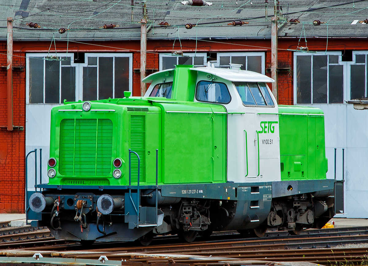 Im neuen grün-weißen Outfit der SETG....
Die SETG V100.51 alias  211 237-3 (92 80 1211 237-3 D-SRA) der Salzburger Eisenbahn TransportLogistik GmbH, ex DB 211 237-3, ex DB V 100 1237, steht am 22.06.2019 vor dem Siegener Ringlokschuppen. Hier bei Rail-Design Bäcker hat sie vor kurzem ihre neue Lackierung bekommen, wie immer ist sie sehr gut gelungen.
Eigentlich steht die Lok auch in ihrer alten Heimat, denn sie war bei der DB dem BW Siegen zugeordnet.
Viele Quellen  schreiben als NVR-Kennung D-SETG, aber angeschrieben ist D-SRA für S-Rail GmbH (Freilassing) ein Tochterunternehmen Salzburger Eisenbahn TransportLogistik GmbH.

Im März 2019 konnte ich sie noch in Hamburg in northrail Outfit fotografieren, siehe https://hellertal.startbilder.de/bild/Deutschland~Unternehmen~Northrail/656611/die-northrail-211-237-3-92-80.html

Die V 100.10 (West) wurde 1961 von Krupp unter der Fabriknummer 4347 	gebaut und als V 100 1237 an die Deutsche Bundesbahn geliefert, zum 01.01.1968 	erfolgte die Umzeichnung in 211 237-3 und bereits 1987 die Ausmusterung bei der DB. 1990 ging sie über On Rail Gesellschaft für Eisenbahnausrüstung und Zubehör mbH an die Solvay Österreich GmbH, Werk Ebensee (A)  als 211 237-3 „Didi 1“.
2010 kam sie wieder nach Deutschland zur northrail GmbH in Kiel als Mietlok bis sie Ende 2018 an die SETG verkauft wurde.

Die BR 211 (V100.10)
Die Baureihe V 100 ist ein von der Deutschen Bundesbahn (DB) Ende der 1950er Jahre beschaffter Lokomotivtyp mit dieselhydraulischem Antrieb, der auf nicht elektrifizierten Nebenbahnen die dort verwendeten Dampflokbaureihen ersetzen sollte. Die Baureihe V 100 wurde in mehreren verschiedenen Ausführungen produziert. Die Baureihe V 100.10 (BR 211) sollte im leichten Reise- und Güterzugdienst auf Nebenstrecken eingesetzt werden. Dieser Loktyp wurde 1956 von dem Bundesbahn-Zentralamt München zusammen mit der MaK für die DB entwickelt.

Die Lokomotiven der V-100-Familie haben zwei Drehgestelle mit je zwei angetriebenen Radsätzen. Als Motoren wurden in den Ursprungsausführungen schnelllaufende Zwölfzylinder-V-Motoren von Maybach, Mercedes-Benz oder MAN verwendet. Die Kraftübertragung vom Motor auf die Radsätze erfolgt über ein hydrodynamisches Getriebe mit zwei Drehmomentwandlern und einer Strömungskupplung und nachgeschaltetem mechanischem Zweigang- und Wendegetriebe über Gelenkwellen auf die einzelnen Radsatzvorgelege in den Drehgestellen. Die Drehgestelle haben einen geschweißten H-förmigen Rahmen mit zwei Längs- und zwei Querträgern. Auf den Drehgestellen stützt sich der aus gewalzten Stahlprofilen und Blechen ebenfalls als Schweißkonstruktion gefertigte Lokomotivrahmen ab. Zur Dämpfung der Drehbewegungen der Drehgestelle gegenüber dem Lokrahmen sind beiderseits der Drehzapfen Stoßdämpfer angeordnet.

Im Spätherbst 1958 wurden die ersten sechs Erprobungsmaschinen ausgeliefert. Die als V 100 001 bis 005 eingereihten Loks wurden mit einem 809 kW (1.100 PS) starken Motor ausgerüstet. Die V 100 006 erhielt jedoch einen Motor mit 993 kW (1.350 PS) Leistung. Die letztgenannte Lokomotive bildete die Grundlage für die V 100.20, die spätere Baureihe 212. Die V 100 007 wurde als siebte Erprobungslok von der Maschinenbau Kiel (MaK) zunächst auf eigene Rechnung gebaut. Sie war die erstgebaute V 100 überhaupt und stand dem BZA München bereits vier Monate vor Ablieferung der restlichen Erprobungsloks für Versuchsfahrten zur Verfügung. 

Erste Wahl für eine Lokomotive in der Leistungsklasse bis 1.100 PS wäre das bewährte hydraulische Dreiwandler-Getriebe LT306r aus der V 200.0 gewesen. Dieses Getriebe entsprach allerdings nicht mehr dem neuesten technischen Stand und bot keine Reserven zur Steigerung der Eingangsleistung über 1.100 PS hinaus. Die DB ließ deshalb von Voith ein neues Getriebe L216rs in Wandler-Wandler-Kupplung-Ausführung entwickeln. Durch Verringerung der Übersetzung zwischen Getriebeeingangswelle und Hohlwelle ließ sich das Getriebe an höhere Motorleistungen anpassen. Dies wurde später für die Baureihe 212 genutzt. Das Getriebe ist als Einwellen-Getriebe konstruiert, das heißt die Pumpenräder laufen auf einer Hohlwelle, in der die Sekundärwelle mit den Turbinenrädern liegt. Die Leiträder sind feststehend mit dem Getriebegehäuse verbunden. An den hydraulischen Teil schließt sich das mechanische Nachschaltgetriebe an, bestehend aus Wende- und Stufenschaltung. 

1961 begann man dann mit der Serienlieferung, die bis 1963 andauerte. Neben MaK wurden die Loks auch von Deutz, der Maschinenfabrik Esslingen, Henschel, Jung, Krauss-Maffei und Krupp gefertigt.

In den Serienlokomotiven kamen überwiegend Motoren von Maybach und Mercedes-Benz zum Einsatz. Die in geringen Stückzahlen beschafften Motoren von MAN waren bis spätestens 1980 vollständig ersetzt. 

Im Rahmen der Umnummerierung der Triebfahrzeuge der Deutschen Bundesbahn im Jahre 1968 wurde die V 100.10 als Baureihe 211 eingeordnet. Die Loks wurden 1994 von der Deutschen Bahn AG übernommen.

Nach fast vierzig Jahren Einsatz musterte man die letzte Maschine im Jahr 2001 aus. 

TECHNISCHE DATEN:
Spurweite: 1.435 mm
Achsfolge: B'B'
Eigengewicht: 63,0 t
Länge über Puffer: 	12.300 mm
Drehzapfenabstand: 6.000 mm
Achsstand im Drehgestell: 2.200 mm
größte Breite: 3.115 mm
größte Höhe über Schienenoberkante: 4.275 mm
kleinster befahrbarer Gleisbogen: 100 m
Treibraddurchmesser: 950 mm
Höchstgeschwindigkeit: 100 km/h
Antrieb: dieselhydraulisch
Leistung:	809 kW (1.100 PS)
Nenndrehzahl: 1.500 U/min
Anfahrzugkraft: 177 kN
Kraftübertragung:	hydraulisch
Kupplungsart:	Schraubenkupplung
