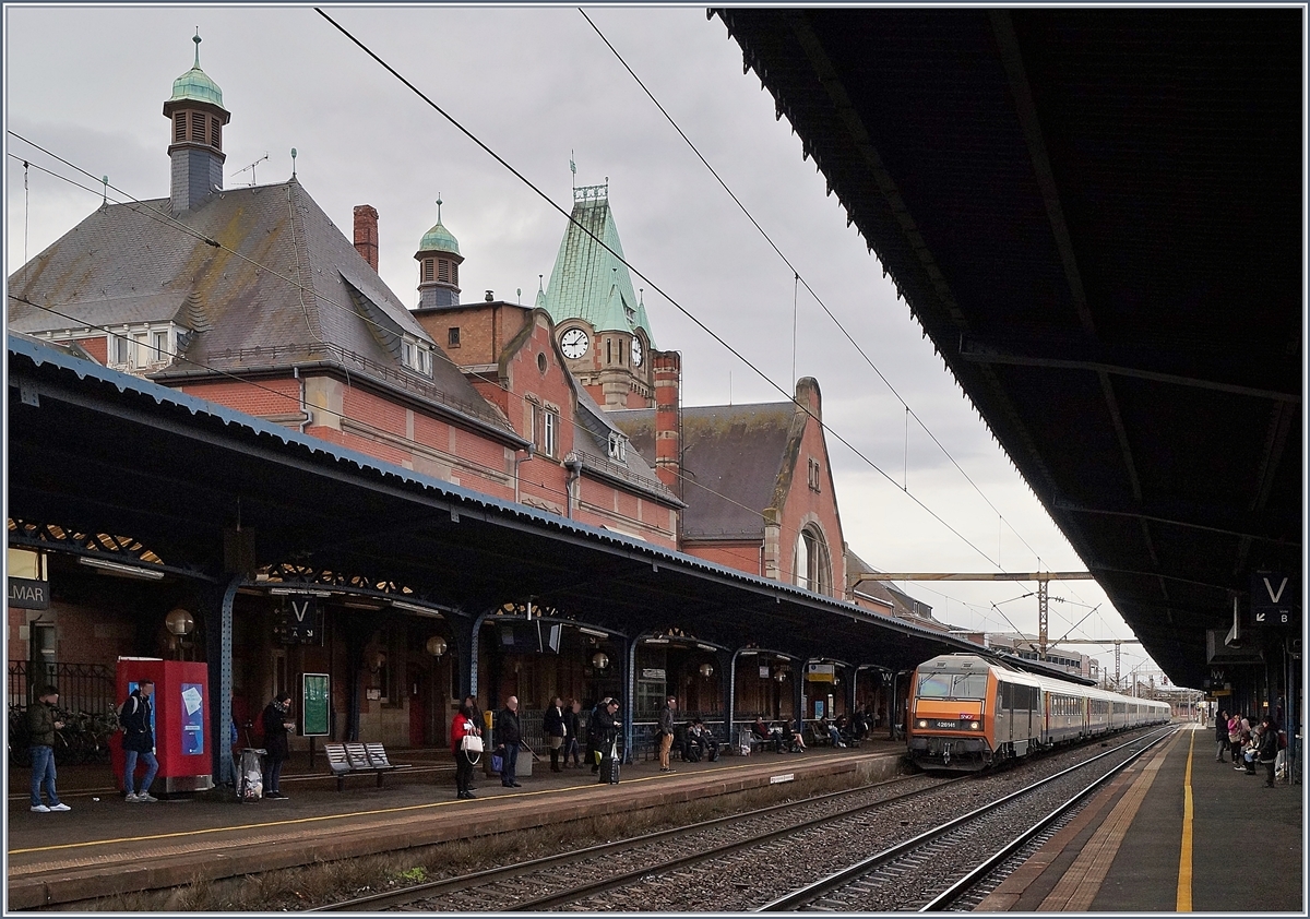 Immer wieder eindrücklich sind die 200 km/h schnellen TER 200, die zwischen Strasbourg und Basel verkehren. Das Bild zeigt die SNCF BB 26 141 (Sybic) welche mit ihrem TER 200 96214 in Colmar eintrifft.
Obwohl das schöne Empfangsgebäude in Colmar an ein Schottisches Schloss erinnert, wurde es nach angepassten Plänen des Bahnhofs von Danzig gebaut und 1907 eingeweiht. 13. März 2018