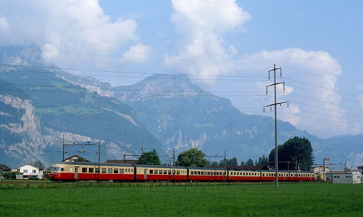 In den 1980er Jahren der Starzug auf der Gotthardbahn: Ein RAe TEE II ist als TEE Gottardo im Juli 1983 bei Flüelen in Richtung Süden unterwegs. Leider stehen an dieser Stelle heute Lärmschutzwände (Neubearbeitung eines bereits bei Bahnbilder.de veröffentlichten Bildes).