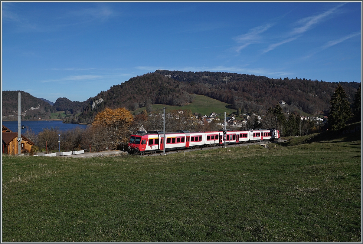 Kurz nach Les Charbonnières ist der TRAVY Regionalzug 6019 auf dem Weg nach Le Brassus. Der Zug besteht aus dem führenden Steuerwagen ABt NPZ DO TR 50 85 39-43 984-6 CH-TVYS, dem nachfolgenden Zwischenwagen B NPZ DO TR 50 85 29-43 384-1 CH-TVYS und dem schiebenden TRAVYS RBDe 560 384 (UIC RBDe 560 DO TR 94 7 560 384-0 CH-TVYS). Im Hintergrund ist der Lac Brenet zu erkennen. 

14. November 2020