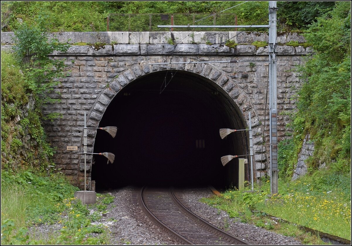 Mal eine technische Kuriosität statt bunter Bilder.

Die Strecke von Neuenburg nach La Chaux-de-Fonds brauchte einen langen Scheiteltunnel unter dem Col de la Vue des Alpes. Da offenbar einfacher zu realisieren, gab es in Convers einen Zwischenangriff und eine leicht verlängerte Strecke. Hier das Tunnelportal des Des Loges Tunnels. Dann folgt eine 125 m lange Kurve in den nächsten Tunnel. Les Convers, Juli 2018.

Vom anderen Tunnelportal zeigt Stefan eine Aufnahme: http://igschieneschweiz.startbilder.de/bild/schweiz~e-loks~re-465-bls-2/711292/die-bls-re-465-002-ist.html