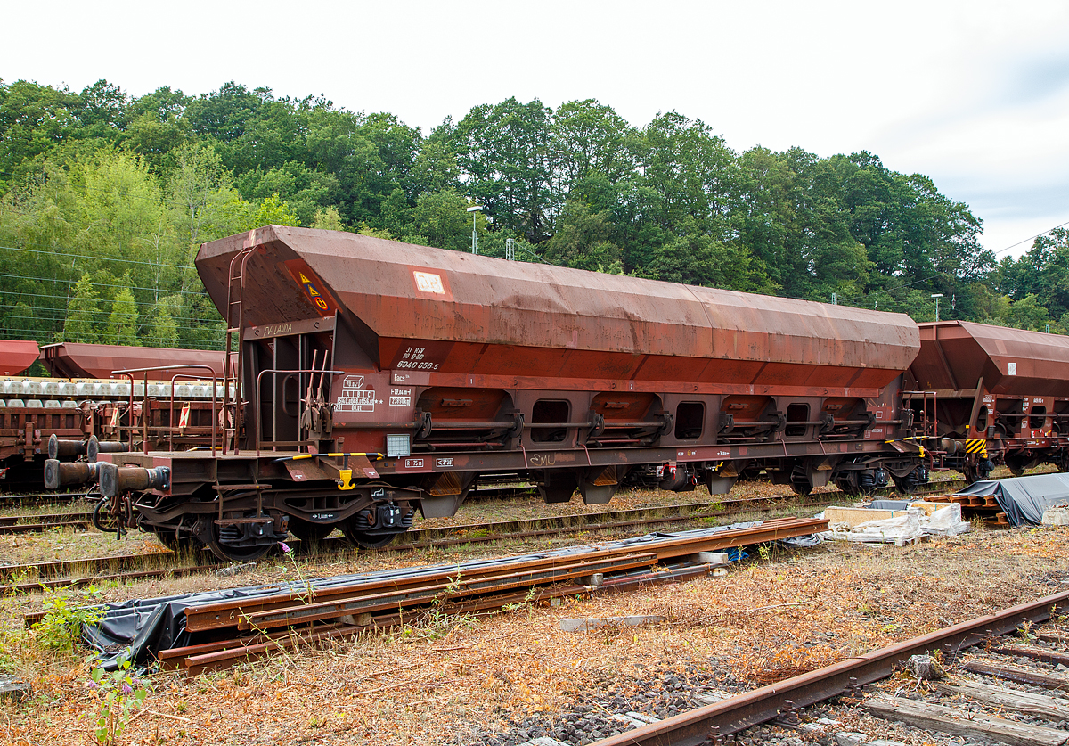 Offener Drehgestell-Schüttgutwagen mit dosierbarer Schwerkraftentladung und vier Radsätzen, 31 80 6941 656-5 D-DB, Gattung Facs 124, der DB Cargo Deutschland AG, abgestellt am 09.08.2019 in Betzdorf/Sieg.

Die DR ließ zwischen 1978 und 1980 bei ANF Industrie (Frankreich) über 1.450 vierachsige offene Selbstentladewagen mit vier Kammern bauen, die zunächst als Eads-y (5970) eingereiht werden. Bei der DB AG werden die Wagen 1994 in Facs 124 umgezeichnet.

Bei den offenen Selbstentladewagen hat der Laderaum die Form mehrerer nebeneinander stehender Trichter. Der Entladevorgang erfolgt über die Schwerkraft des Ladegutes.
Mehrere Auslauföffnungen mit Drehschiebern ermöglichen die restlose Entladung des Wagens nach der einen oder anderen Seite. Die Menge ist regulierbar - so wie es zum Beispiel für die Entladung über Förderband erforderlich ist. Geeignet sind die Wagen für den Transport nicht nässeempfindlicher Güter in loser Schüttung. Die Drehschieber über einer Einrichtung auf der Bühne an einer Stirnseite des Wagens können einzeln bedient werden.

Der Wagen ist für den Transport von Nässe unempfindlichen Schüttgütern vorgesehen. Das Untergestell besteht aus miteinander verschweißten Blechen und Walzprofilen. Der Wagenkasten ist eine Schweißkonstruktion und besteht aus vier Trichtern. Querrippen teilen den Wagenkasten in vier Räume, von denen jeder an seinem Unterteil zwei Entladeöffnungen aufweist, die sich an beiden Seiten der horizontalen Mittellinie des Wagens befinden. Über jeder Entladeöffnung ist am Kastenblech eine Stütze für einen Vibrator angeschraubt.
Die acht kreisförmig ausgebildeten Wölbschieber sind auf Rollen gelagert und verschieben sich auf Laufbahnen, die außerhalb der Rinnen angebracht sind. Unter jeder Entladeöffnung sind eine feste und eine schwenkbare Auslaufrutsche angeordnet. Die schwenkbaren Auslaufrutschen werden einzeln durch einen Hebel betätigt, der in der Nähe der Rutsche angebracht ist. Die Betätigung der Wölbschieber erfolgt von der Bedienungsplattform aus. Die Entladung des Wagens erfolgt nach Öffnen der Schieber durch die Schwerkraft des Ladegutes. Für den Zugang zur Bedienungsplattform sind zwei Auftritte mit Gitterrosten (500 x 160 mm) vorhanden.

Das Entfernen von Ladegutresten in der Be- oder Entladestraße ist nur durch leichte Gummihammerschläge auf die äußeren Behälterwandungen gestattet oder durch den Einsatz von Pressluftlanzen im Laderaum! 

TECHNISCHE DATEN:
Hersteller: ANF Industrie (Frankreich)
Spurweite: 1.435 mm
Achsanzahl: 4 (in 2 Drehgestellen)
Länge über Puffer: 19.040 mm
Drehzapfenabstand: 14.000 mm
Achsabstand im Drehgestell: 1.800 mm
Größe der Beladeöffnung: 1.800 x 15.300 mm
Laderaum:  70 m³
Breite der festen Auslaufrutschen: 600 mm
Breite der schwenkbaren Auslaufrutschen: 476 mm
Wagenhöhe:  4.000 mm
Höchstgeschwindigkeit: 100 km/h (beladen) / 120 km/h (leer)
Maximales Ladegewicht: 56,0 t (ab Streckenklasse C)
Eigengewicht: 23.890 kg
Drehgestell-Bauart: Y 25 Cs – 639
Kleinster bef. Gleisbogenradius: 75 m
Bauart der Bremse:  KE-GP
Intern. Verwendungsfähigkeit: RIV