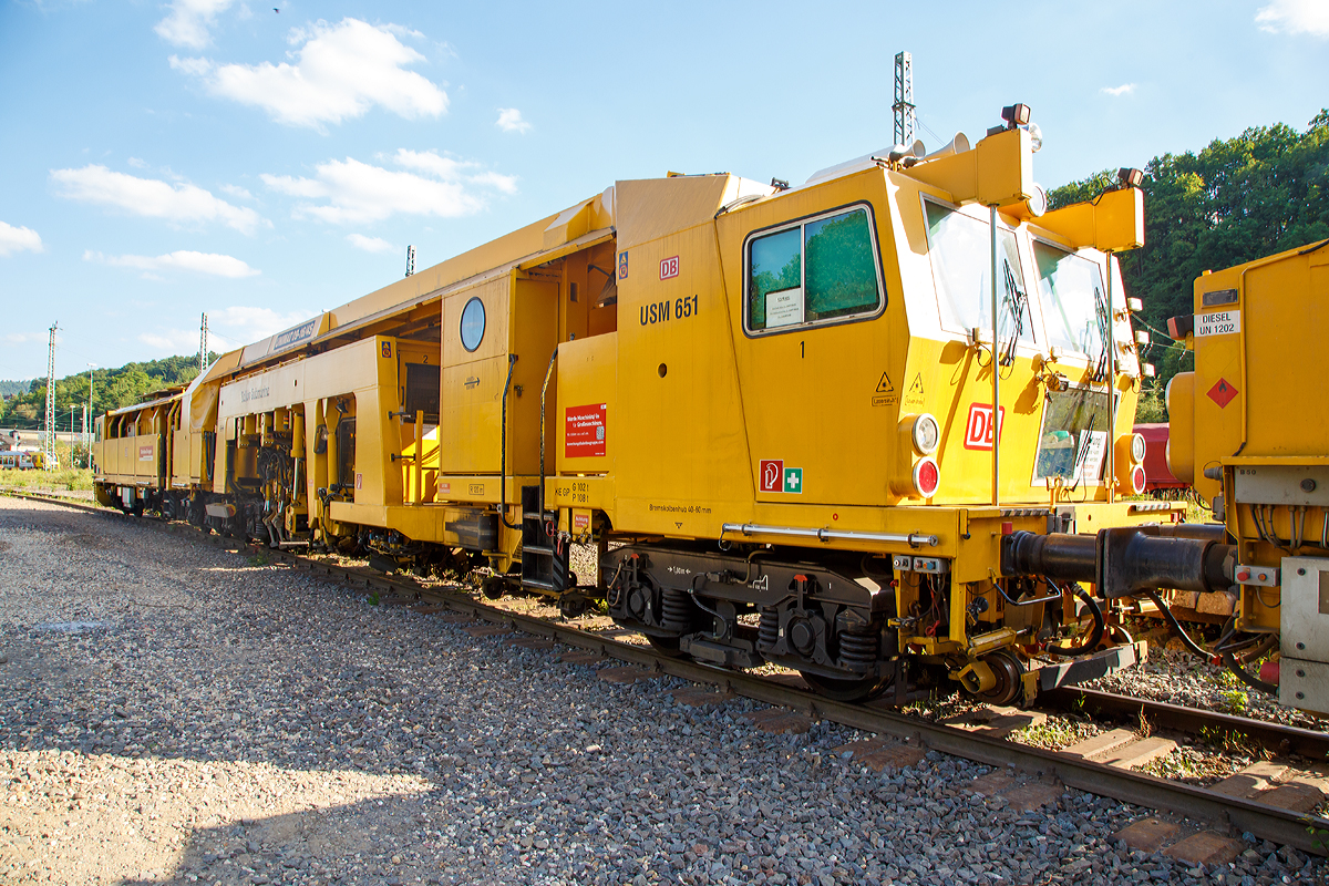 
Plasser & Theurer Universalstopfmaschine UNIMAT 09 - 16 / 4S (Schweres Nebenfahrzeug Nr. 97 43 51 001 17-3)  USM 651  „Yellow Submarine“  der DB Bahnbau Gruppe, abgestellt am 14.06.2017 in Betzdorf/Sieg abgestellt. Ehemals gehörte die Maschine der DB Netz AG, Maschinenpool (Netz Instandhaltung).

Die Universalstopfmaschine mit der internen DB Bezeichnung USM 651 wurde 2002 von Plasser & Theurer in Linz (A) unter der Fabriknummer 3023 gebaut.

Die Universalstopfmaschine Unimat 09-16/4S für Gleise und Weichen verfügt über vier unabhängig voneinander arbeitende Stopfaggregate mit insgesamt 16 Stopfpickeln. Bei der Gleisdurcharbeitung ist kontinuierliches Fahren und zyklisches Stopfen bis weit in den Weichenbereich hinein möglich

Funktionsmerkmale der USM Unimat 09-16/4S: 
- die vier Stopfaggregate können gedreht, einzeln seitlich verschoben und somit vor jedem Stopfgang optimal positioniert werden
- für das Stopfen von Langschwellen werden die außen liegenden Stopfaggregate mit horizontalen Teleskop-Führungssäulen seitlich ausgefahren (Vierstrang-Stopfung)
- kontinuierliches Fahren und zyklisches Stopfen bis weit in den Weichenbereich hinein
- Durcharbeitung von Weichen erfolgt mit Dreistrang-Hebung und Vierstrang-Stopfung
- eine automatisch arbeitende Zusatzeinrichtung gewährleistet die Hebung des dritten Stranges
- Richtungslaser zum Verlängern der Messbasis in der Geraden
- 6-Kanal-Schreiberanlage zur Dokumentation der Gleißlage und Arbeitsqualität 
- Vibrationsverdichter
- automatischer Leitcomputer ALC mit EM-SAT Datenverarbeitung
- automatische Toleranz-Überwachung für Arbeitsqualität der Maschine
- Korrektursteuerung für Höhe, Längshöhe, Richtung, Überhöhung

TECHNISCHE DATEN:
EBA-Nummer: EBA 00 A 11 003
Spurweite: 1.435 mm (Normalspur)
Anzahl der Achsen: 8 davon 4 angetrieben
Achsfolge: 2' 2'+Bo' Bo' 
Länge über Puffer:  33.140 mm
Drehzapfenabstände: 10.000 mm / 3.500 mm / 14.000 mm
Achsabstand im Drehgestell: 1.800 mm
Raddurchmesser (neu): 920 mm
Eigengewicht: 131.000 kg
Nutzlast: - t
Zul. Anhängelast: 60 t
Leistung: ca. 500 kW 
Zur Mitfahrt zugel. Personenzahl: 6
Kleister befahrbarer Gleisbogen: R = 120 m (Arbeitsradius  min.  150 m)
Zugelassen für Streckenklasse: C2 und höher
Höchstgeschwindigkeit: 100 km
Bremse: KE-GP mZ K
Bremsgewichte: G 102 t / P 108 t

Arbeitsleistung bei Durcharbeitung im Gleis:  600 m/h
Arbeitsleistung bei Durcharbeitung von Weichen : 1 /h