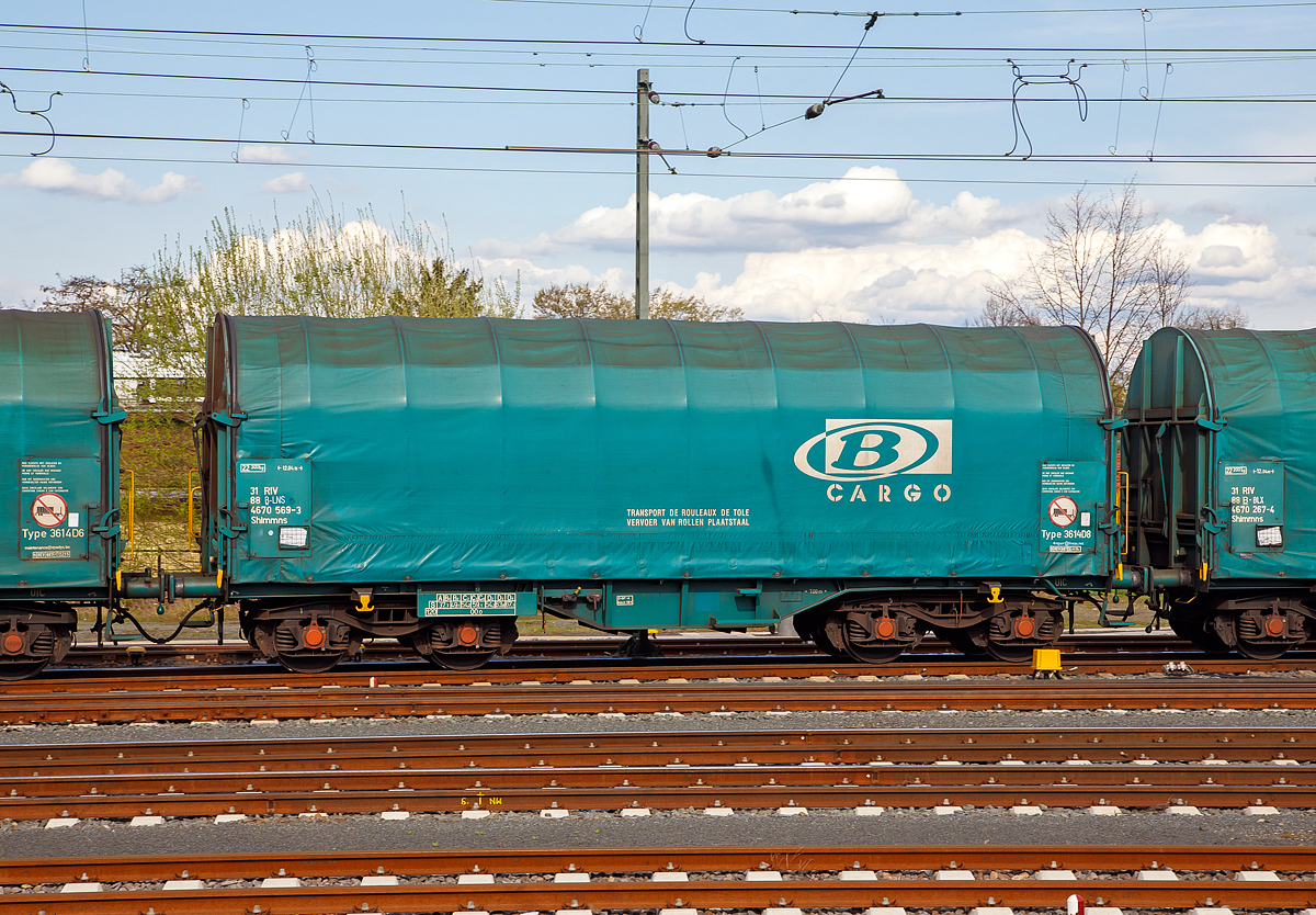 Vierachsiger Drehgestell-Flachwagen mit verschiebbarem Planenverdeck und Lademulden fr Coiltransporte, 31 88 4670 569-3 B-LNS, der Gattung Shimmns (LINEAS Wagon Type 3614D8), der Lineas Group nv/sa (ex B-Logistics, ex B Cargo) am 14.04.2018 im Zugverband bei der Durchfahrt im Bahnhof Friedberg (Hessen).

Diese Wagen sind speziell fr den Transport witterungsempfindlicher Blechrollen (Coils) bestimmt. Er besitzt feste Stirnwnde, 5 fest im Untergestell eingebaute Lademulden. Die Wagenabdeckung erfolgt mit einer PVC-beschichteten Gewebeplane, die auf 11 Rohrrahmen aufliegt. ber Laufwagen ist das Planendach in Wagenlngsrichtung verschiebbar. Die Verriegelung des Planendaches an den Stirnwnden erfolgt ber eine 4-Punkt-Zentralverriegelung, die sowohl vom Erdboden als auch von der Rampe aus bedient werden kann. Das Planenverdeck lsst sich an einem Wagenende so weit zusammenschieben, dass ca. 2/3 der Ladeflche zur Beladung freigegeben wird. Hierdurch ist eine einfache Beladung des Wagens sowohl von oben als auch von der Seite aus mglich. 

TECHNISCHE DATEN:
Spurweite: 1.435 mm
Achsanzahl: 4 (in 2 Drehgestelle)
Lnge ber Puffer: 12.040 mm
Lnge der Ladeflche: 10.800 mm
Drehzapfenabstand: 7.000 mm
Achsabstand im Drehgestell: 1.800 mm
Eigengewicht: 22.300 kg
Hchstgeschwindigkeit:  100  km/h (beladen) / 120 km/h (leer)
Maximales Ladegewicht: 67,1 t (Streckenklasse D4)
Kleinster bef. Gleisbogenradius: 35 m
Bauart der Bremse: O-GP-A
Intern. Verwendungsfhigkeit: RIV

Bedeutung der Gattung Shimmns:
S     = Drehgestell-Flachwagen in Sonderbauart
h     = fr den Transport liegend verladener Coils geeignet
i     = mit beweglicher Abdeckung und festen Stirnwnden
mm    = Ladelnge kleiner 15 m  (bei vierachsigen Wagen)
n     = Maximale Tragfhigkeit ber 60 t
s     = Hchstgeschwindigkeit bis zu 100 km/h (beladen)
