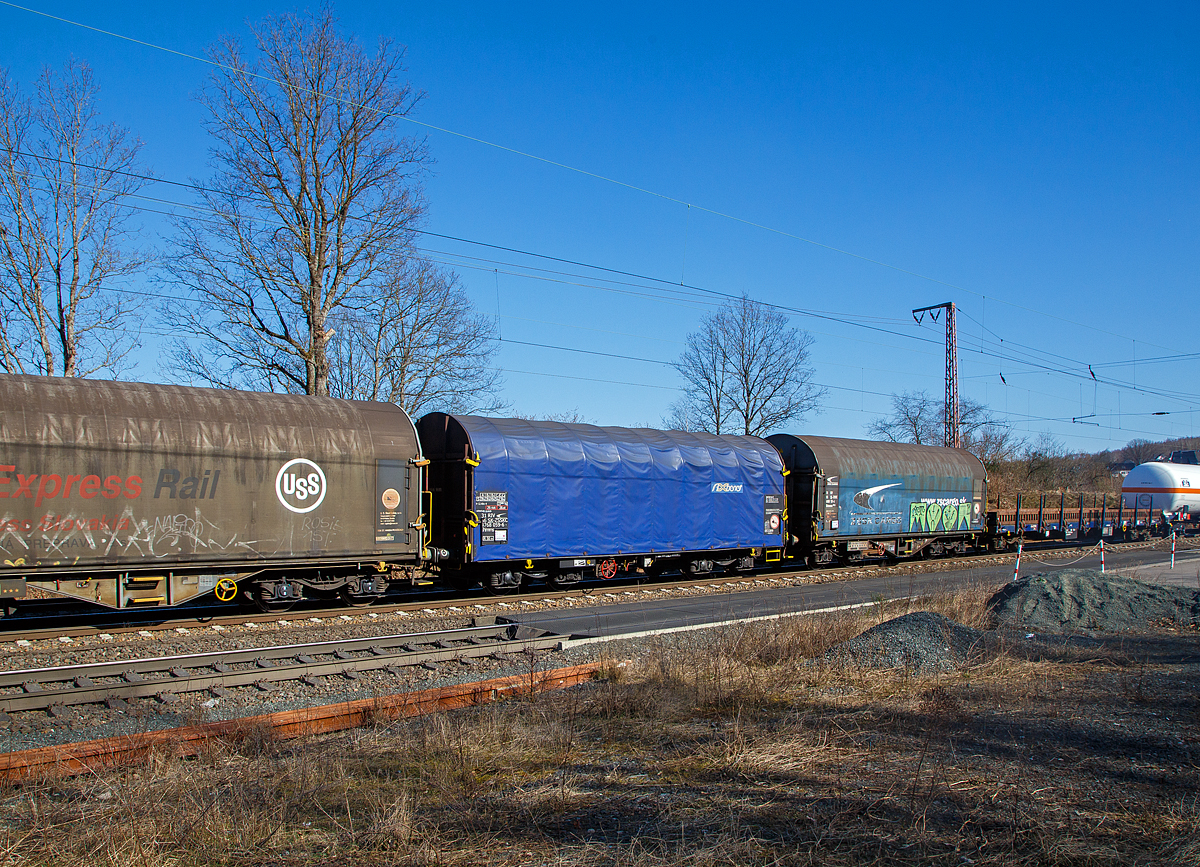 Vierachsiger Drehgestell-Flachwagen mit verschiebbarem Planenverdeck und Lademulden für Coiltransporte, 31 56 4768 059-6 SK-ZSSKC, der Gattung Shimms, des slowakischen Wagonvermieters AXBENET s.r.o. (Trnava), eingestellt durch die ZSSK Cargo (Železničná spoločnosť Cargo Slovakia), am 10.03.2022 im Zugverband bei einer Zugdurchfahrt in Rudersdorf (Kr. Siegen).