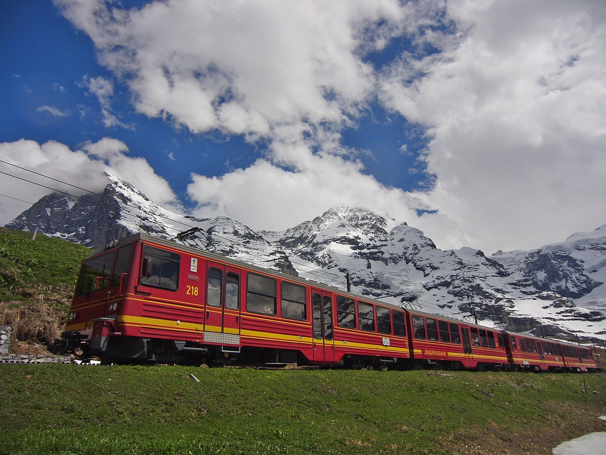 Vor dem Massiv des 3970 m hohen Eigers mit der wolkenverhangenen Spitze der Eigernordwand und des 4107 m hohen Mönchs befindet sich der 2002 in Betrieb genommene Triebwagen 218 kurz vor der Einfahrt in den Ziel- und Endbahnhof Kleine Scheidegg.