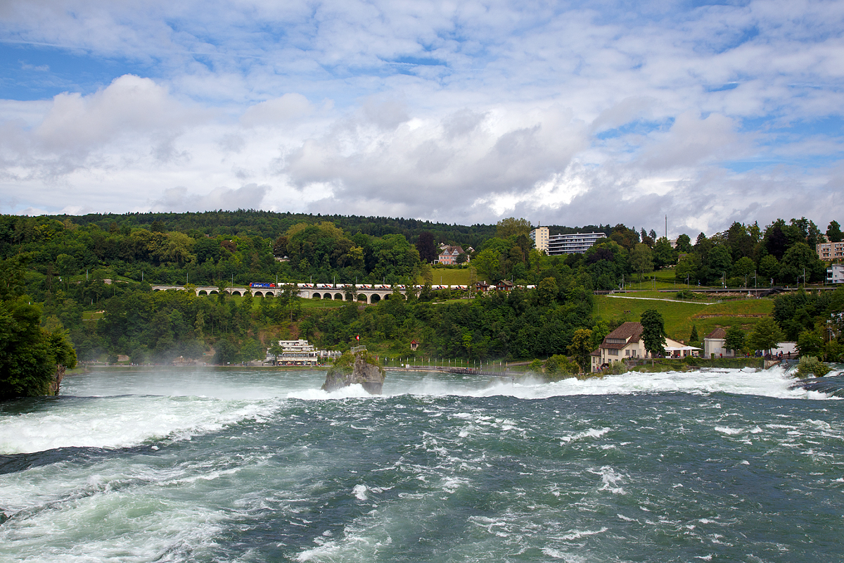 
Während am Rheinfall rissige Wassermassen hinabfallen, zieht die SBB Cargo Re 620 060-4  Tavannes  (ex SBB Re 6/6 11660  Tavannes ) am 18.06.2016 einen  Holcim Zement-Silowagen-Zug (Wagen der Gattung Uacns) über den Hangviadukt in Neuhausen in Richtung Zürich. 