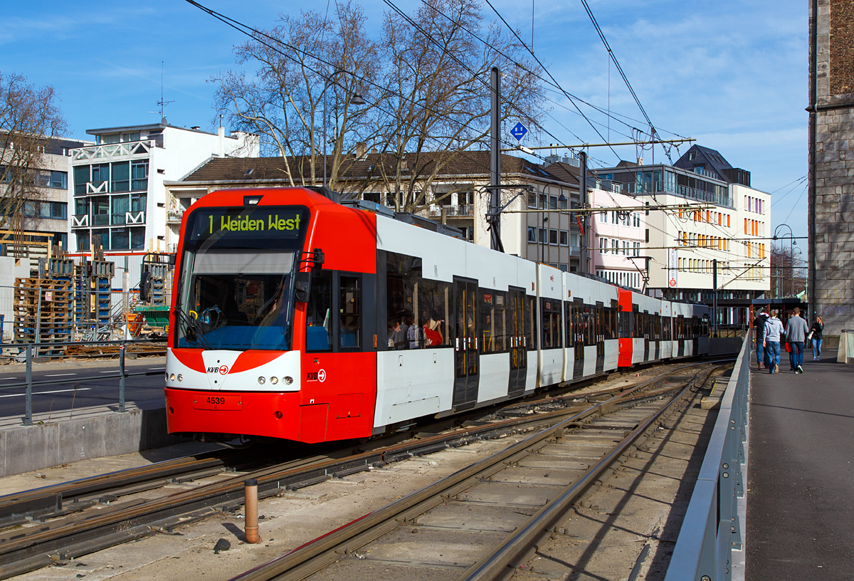 
Zwei gekuppelte dreiteilige Zweirichtungs-Niederflur-Gelenktriebwagen vom Typ Bombardier Flexity Swift der KVB Serie K 4500  der KVB (Kölner Verkehrs-Betriebe AG) haben am 08.03.2015 als Linie 1 (nach Weiden West) gerade die Station Heumarkt verlassen, vorne der Triebwagen 4539.

Der Bombardie Flexity Swift ist eine Familie von Stadtbahnwagen des Herstellers Bombardier Transportation, die erstmals 1995 durch die Kölner Verkehrs-Betriebe (KVB) eingesetzt wurde. Heute werden die Fahrzeuge von mehreren Verkehrsbetrieben in Europa und den USA eingesetzt. Dazu gehören u. a. Bonn, Frankfurt am Main, Istanbul, Köln, London-Croydon, Minneapolis, Rotterdam, Stockholm und Manchester. Die Fahrzeuge sind sowohl in einer Niederflur- als auch einer Hochflur-Version lieferbar. In Deutschland sind sie hauptsächlich unter den Typbezeichnungen der KVB (K4000, K4500, K5000) oder der VGF (U5) bekannt.

Das Fahrzeugkonzept des K4500 baut auf dem Konzept des modernen hochflurigen Stadtbahnwagens K5000 unter besonderer Berücksichtigung und Nutzung einer großen Anzahl von bereits bei der KVB zum Einsatz kommenden Teilen, Modulen und Systemen auf. Er ähnelt sehr Typ K4000 ist aber technisch näher mit dem K5000 verwand. In den Jahren 2005 bis 2007 wurden insgesamt 69 dieser Fahrzeuge an die KVB geliefert, wobei die elektrische Ausrüstung von Vossloh Kiepe ist.  Grund dieser Umwandlung einer Bestellung für K5000-Fahrzeuge war eine Entscheidung der Kölner Stadtverordneten, einen Teil des Stadtbahnnetzes komplett für den Einsatz von Niederflurfahrzeugen herzurichten.

Jedes Fahrzeug ist mit zwei direkt an der Netzspannung betriebenen IGBT-Traktionsumrichtern ausgestattet. Diese speisen je zwei wartungsarme, voll abgefederte Drehstrom-Asynchronmotoren. Zur redundanten Versorgung des Bordnetzes sind zwei IGBT-Bordnetzumrichter vorhanden. Die Klima- und Temperierungsanlagen werden von zwei separaten IGBT-Hilfsbetriebeumrichtern versorgt.
Jeweils ein Traktionsumrichter, ein Bordnetzumrichter und ein Hilfsbetriebeumrichter sind in einem Dachgerätegehäuse gut zugänglich auf dem Dach installiert. Über den Zugbus können beliebig gemischte Zugverbände zwischen K4000 und K4500 Stadtbahnwagen von bis zu vier Fahrzeugen gesteuert werden.

TECHNISCHE DATEN der  K 4500:
Bauart: 6-achsiger Niederflurgelenktriebwagen für Zweirichtungsbetrieb
Typ: K4500
Spurweite:	1.435 mm (Normalspur)
Achsfolge: Bo‘+2‘+Bo‘
Fahrzeuglänge über Kupplung:  29.020 mm
Wagenkastenlänge: 28.540 mm
Wagenkastenbreite: 2.650 mm
Wagenkastenhöhe über SOK: 3.644 mm
Fahrwerks-Mittenabstand: 10.505 mm
Raddurchmesser: 660 mm (neu) / 580 mm (abgenutzt)
Leergewicht:  39.400 kg
Sitzplätze: 58
Stehplätze (4 Personen/m²): 125
Höchstgeschwindigkeit: 80 km/h
Nennleistung: 4 x 120 kW (480 kW) 
Motor: 4 Stück querliegender, eigenbelüfteter Drehstrom-Asynchronmotor, voll abgefedert, vom Typ 1MLU 3441K/4
Stromsystem: 750 V DC (=) über Oberleitung
Minimaler horizontaler Kurvenradius: 20 m
Maximal befahrbare Steigung : 60‰
Niederfluranteil: 	72%

Quellen: Bombardier, Vossloh Kiepe und Wikipedia
