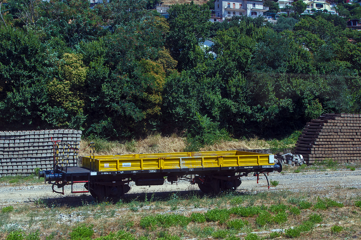 Zweiachsiger Flachwagen mit Bremserplattform und Seitenwandklappen abgestellt am 16.07.2022 beim Bahnhof Agropoli (Region Kampanien – Italien). Aufnahme aus einem IC durch die Scheibe.

TECHNISCHE DATEN (laut Anschriften):
Spurweite: 1.435 mm
Achsanzahl: 2
Länge über Puffer: 9.240 mm
Achsabstand: 4.500 mm
Höchstgeschwindigkeit: 55 km/h
Max. Zuladung: 10.500 kg
Nutzlast: 12.500 kg 
Handbremse: Ja
