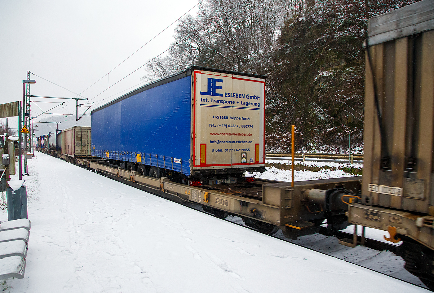 Achtachsiger niedrig gelegte Doppelwagen Jumbo II / Mega II (Trag-/Taschenwagen-Doppeleinheit) der Gattung Sdggmrrss, 83 85 493 3 329-5 CH-HUPAC, der Hupac Intermodal SA, am 19.01.2023 im Zugverband bei einer Zugdurchfahrt in Scheuerfeld (Sieg) in Richtung Köln.Hier beladen vorne mit einem Sattelzugauflieger und mit einem Container.

Diese Wageneinheiten bestehen aus einer niedrigen Tragwagenhälfte für Container und Wechselbehälter („CT“) und einer niedrigen Taschenwagenhälfte („SK“). Die beiden Wagenhälften sind mit einer, im Normalbetrieb nicht zu trennenden, (von den Waggons der RoLa, Saadkms 690, abgeleiteten) Kurzkupplung verbunden.
