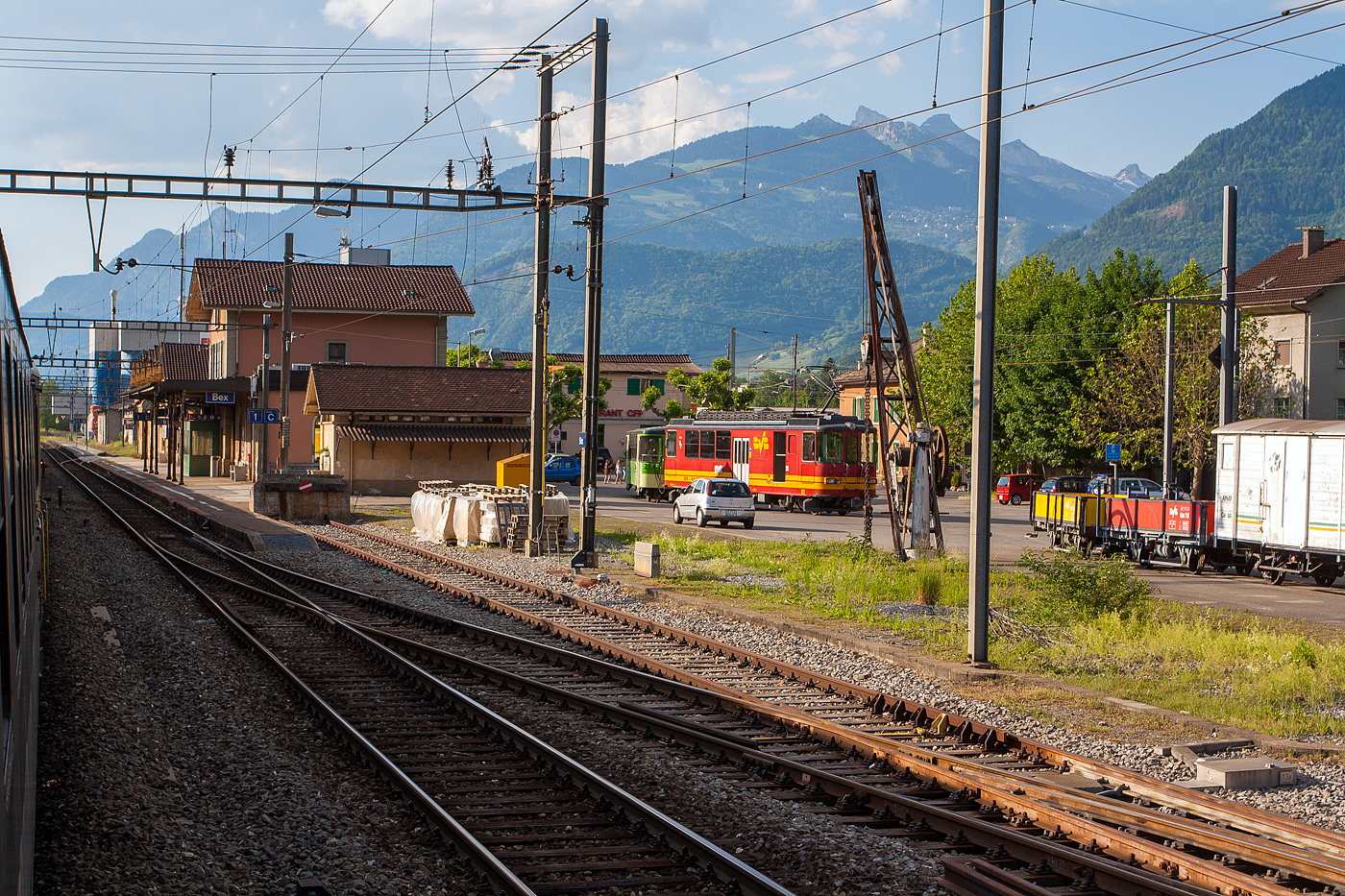 Blick aus unseren SBB Zug heraus am 28 Mai 2012 auf dem Bahnhof Bex, damals konnte man die Fenster noch ffnen. 

Am Bahnhofsvorplatz steht der tpc BVB BDeh 4/4 82 „Ollon“, ein elektrischer Personentriebwagen mit Gepckabteil fr den gemischtem Adhsions- und Zahnradbetrieb, noch in originaler Farbgebung, mit einem Pendelzug. Damals gingen die Gleise vom Bahnhof nach links Richtung Gterschuppen. Die Wagen vom Pendelzug (Steuerwagen und der Zwischenwagen B 62) hatten schon die neue grne TPC-Farbgebung.