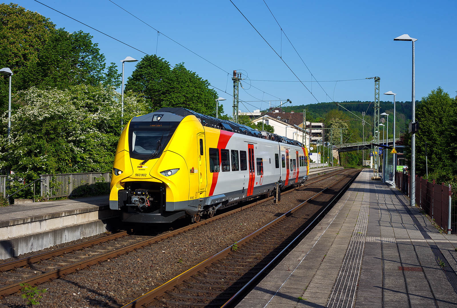 Das ist der neue Klimaschutz am Westerwald....
Einer der drei neuen zweiteiligen Hybridtriebzge (E/Akku) der BR 563 vom Typ SIEMENS Mireo Plus B der HLB (Hessische Landesbahn GmbH). Der HLB 563 802 / 563 902 (94 80 0563 802-8 D-HEB / 94 80 0563 902-6 D-HEB) fhrt am 02 Mai 2025 auf Leerfahrt durch den Bahnhof Kirchen/Sieg in Richtung Betzdorf, hier hat er kurz Hp 0. Der Triebzug fhrt hier sogar im Batteriemodus, denn es kein Stromabnehmer angehoben.  

Der zweiteilige SIEMENS Mireo Plus B wurden 2024/25 von SIEMENS in Krefeld gebaut und im April 2025 an die HLB ausgeliefert.

Auszug aus der Pressemitteilung der HLB:
Alternative Antriebe im Norden von Rheinland-Pfalz: Durchbruch beim Pilotprojekt mit Batteriezgen im Westerwald / Zuschlag an Siemens Mobility fr Mireo Plus B Fahrzeuge

Als Aufgabentrger fr den Nahverkehr auf der Schiene im Norden von Rheinland-Pfalz setzt sich der SPNV-Nord gemeinsam mit seinen Projektpartnern von Bund, Land und Eisenbahnverkehrsunternehmen (EVU) fr den Einsatz von alternativen Antrieben als Abkehr vom Dieselbetrieb ein.

Dabei konnte bereits im letzten Jahr fr die Beschaffung der Fahrzeuge eine Untersttzung aus dem Frderprogramm des Bundesministeriums fr Digitales und Verkehr (BMDV) fr alternative Antriebe gewonnen werden.

Als Besonderheit sollen im SPNV-Nord erstmalig die beiden Antriebstechnologien fr die Dekarbonisierung des Schienenverkehrs, Wasserstoff und Batterieelektrik, nebeneinander im mehrjhrigen Fahrgastbetrieb zum Einsatz kommen mit einer vollstndigen Rckfallebene mit Dieselfahrzeugen.

Das betrifft auch den Pilotbetrieb mit drei batterie-elektrischen Fahrzeugen im Westerwald, der zum Fahrplanwechsel im Dezember 2025 geplant ist. Dieser sieht einen Fahrzeugeinsatz auf der RB 90 Limburg – Au – Siegen (Oberwesterwaldbahn und Siegstrecke) und auf der RB 29 Limburg – Siershahn (Unterwesterwaldbahn) durch die Hessische Landesbahn (HLB) vor. Bei diesem Pilotprojekt wurde jngst ein wichtiger Durchbruch erzielt:

Als Ergebnis der von der HLB dafr durchgefhrten Fahrzeugausschreibung hat Siemens Mobility jetzt den Zuschlag fr drei zweiteilige Mireo Plus B Batteriezge erhalten. Das Fahrzeug mit seiner hohen Antriebsleistung ist fr den anspruchsvollen Einsatz im Westerwald bestens geeignet. Der geplante Einsatz der drei Batteriezge auf den Linien RB 90 und RB 29 umfasst eine Jahresfahrleistung von fast 400.000 Zug-km und ersetzt drei Dieselfahrzeuge. Da die HLB emissionsfreien Bahnstrom bezieht, werden jhrlich fast 1.150 Tonnen CO2 eingespart. Der Betrieb der Batteriefahrzeuge erfordert keine neue Infrastruktur, denn die Wendezeiten in Limburg von ber 20 Minuten auf der RB 29 werden fr die Aufladung der Fahrzeuge ausreichend sein. Bei den auf der RB 90 verkehrenden Batteriefahrzeugen erfolgt dies im elektrifizierten Abschnitt zwischen Au und Siegen. Die Oberwesterwaldbahn (Limburg – Au) ist mit der Lnge von rund 75 km und der zu berwindende Hhe von ca. 350 m derzeit in Deutschland die anspruchsvollste Strecke fr den vorgesehenen Einsatz von Batteriezgen.

Die Ausschreibung der Batteriefahrzeuge war so ausgestaltet, dass die Hersteller die Mglichkeit hatten, die Fahrzeuge in laufende Bestellungen zu integrieren, so dass eine schnelle Lieferzeit in Aussicht gestellt wurde.

Siemens Mobility baut fr den Einsatz im Westerwald drei zweiteilige Mireo Plus B Batteriezge, die durch jeweils drei Tren pro Seite einen schnellen Ein- und Ausstieg ermglichen. Die Zge verfgen fr den Betrieb unter Oberleitung und zum Aufladen der Batterien ber einen Stromabnehmer und verkehren auf den nicht-elektrifizierten Strecken im Batteriebetrieb. Die gerumigen Fahrzeuge bieten den Fahrgsten 126 Sitzpltze und 156 Stehpltze und sind mit einer speziellen Einstiegshilfe ausgestattet, die mobilittseingeschrnkten Menschen das Bahnfahren erleichtert.

Die neuen Batteriezge werden auf der Oberwesterwaldbahn Limburg – Altenkirchen - Au - Siegen, und auf der Unterwesterwaldbahn zwischen Limburg – Montabaur – Siershahn unterwegs sein. Die Strecke der OWB betrgt ca. 115 km, davon sind ca. 75 km ohne Fahrdraht. Es ist vorgesehen die Zge in Limburg und auf dem Teilabschnitt Au – Siegen nachzuladen. Auf der UWB betrgt die nicht elektrifizierte Strecke ca. 35 km. Damit ist ein Zugbetrieb hin und zurck ohne Nachladen mglich. Insgesamt werden die Zge ber 50 Bahnhfe anfahren.

Technik und Fahrzeugaufbau:
Die Triebzge werden nur mit elektrischem Antrieb angeboten. Die Fahrzeugplattform ist mit Jakobs-Drehgestellen und Einzeldrehgestellen, hnlich wie bei den ICE 4 mit innengelagerten Radstzen lieferbar. Die Wagenksten werden in Aluminium-Integralbauweise hergestellt. Bei diesem zweiteiligen Triebzug ruht je ein Wagenkasten auf einen Triebdrehgestell SF 7500 als Enddrehgestell, sowie auf der Hlfte des mittigen Jakobs-Laufdrehgestell SF 7500. 

Die Triebzge werden im Siemens-Werk Krefeld gefertigt. Im Mrz 2020 erhielt Siemens Mobility den ersten Auftrag fr eine zweiteilige Variante des Mireo Plus B die ihren Fahrstrom sowohl aus einer Batterie als auch aus der Fahrleitung erhlt. Die Batterie kann im Stand und whrend der Fahrt aus der Fahrleitung geladen werden. Die Reichweite eines Mireo Plus B im Batteriebetrieb wird mit 80 bis 120 Kilometern angegeben.

Zum Einsatz kommen Lithiumtitanat-Akkumulatoren (LTO) von Toshiba, die unter den Wagenbden verbaut sind. Diese haben eine hohe Zyklenfestigkeit auch bei hohen Ladestrmen, wie sie beim Bremsen und Anfahren auftreten – bei einer Laderate von 10C garantiert der Hersteller seit 2019 mindestens 15.000 Ladezyklen und seit 2022 mindestens 40.000 Ladezyklen.

Unterwesterwaldbahn/Oberwesterwaldbahn:
Am 7. Februar 2023 gab Siemens Mobility bekannt, dass die Hessische Landesbahn (HLB) fr den Einsatz auf den Regionalbahn Linien RB 29 (Limburg (Lahn)–Montabaur–Siershahn) und RB 90 (Limburg/Lahn–Au/Sieg– Siegen) auf der Unterwesterwaldbahn bzw. Oberwesterwaldbahn drei Mireo Plus B bestellt habe. Der Einsatz ist ab Sommer 2025 geplant und soll im Rahmen eines Pilotbetriebes die Eignung von Triebzgen mit alternativen Antrieben auf den topografisch anspruchsvollen Strecken demonstrieren. Der Betrieb soll nach Angaben der HLB jhrlich fast 1.150 Tonnen Kohlenstoffdioxid einsparen.

TECHNISCHE DATEN:
Spurweite: 1.435 mm (Normalspur)
Achsfolge: Bo’-2’-Bo’
Fahrzeuglnge ber Kupplung: 46.560 mm
Drehzapfenanstand: 2 x 17.930 mm
Achsabstand im Triebdrehgestell (Enddrehgestell): 2.300 mm
Achsabstand im Jakobs-Laufdrehgestell: 2.600 mm
Drehgestellplattform: SF 7500 mit innengelagerten Radstzen
Raddurchmesser: 880 mm (neu) / 810 mm (abgenutzt)
Anzahl der Tren je Seite: 3
Eigengewicht im betriebsbereiten Zustand: 92.891 kg
Installierte Leistung: 1.700 kW
Leistungsbertragung: elektrisch
Motoren: 2 Drehstrom-Asynchronmotoren
Hchstgeschwindigkeit: 140 km/h 
Kupplung: Mittelpufferkupplung Schaku Typ 10
Sitzpltze: 126
Bremse: FT C-el-pn-R-A-E-Mg (D)
kleinster befahrbarer Gleisbogen: R 150 m (Normal) / R 100 m (Werkstatt)
Zulassungen: Deutschland (D)

Ein kleiner Nachteil gegenber den LINT-Dieseltriebzgen ist mir aufgefallen, die Gesamt-Fensterflche ist geringer. Ich bin aber sehr gespannt auf den Betriebseinsatz und wie es luft.
