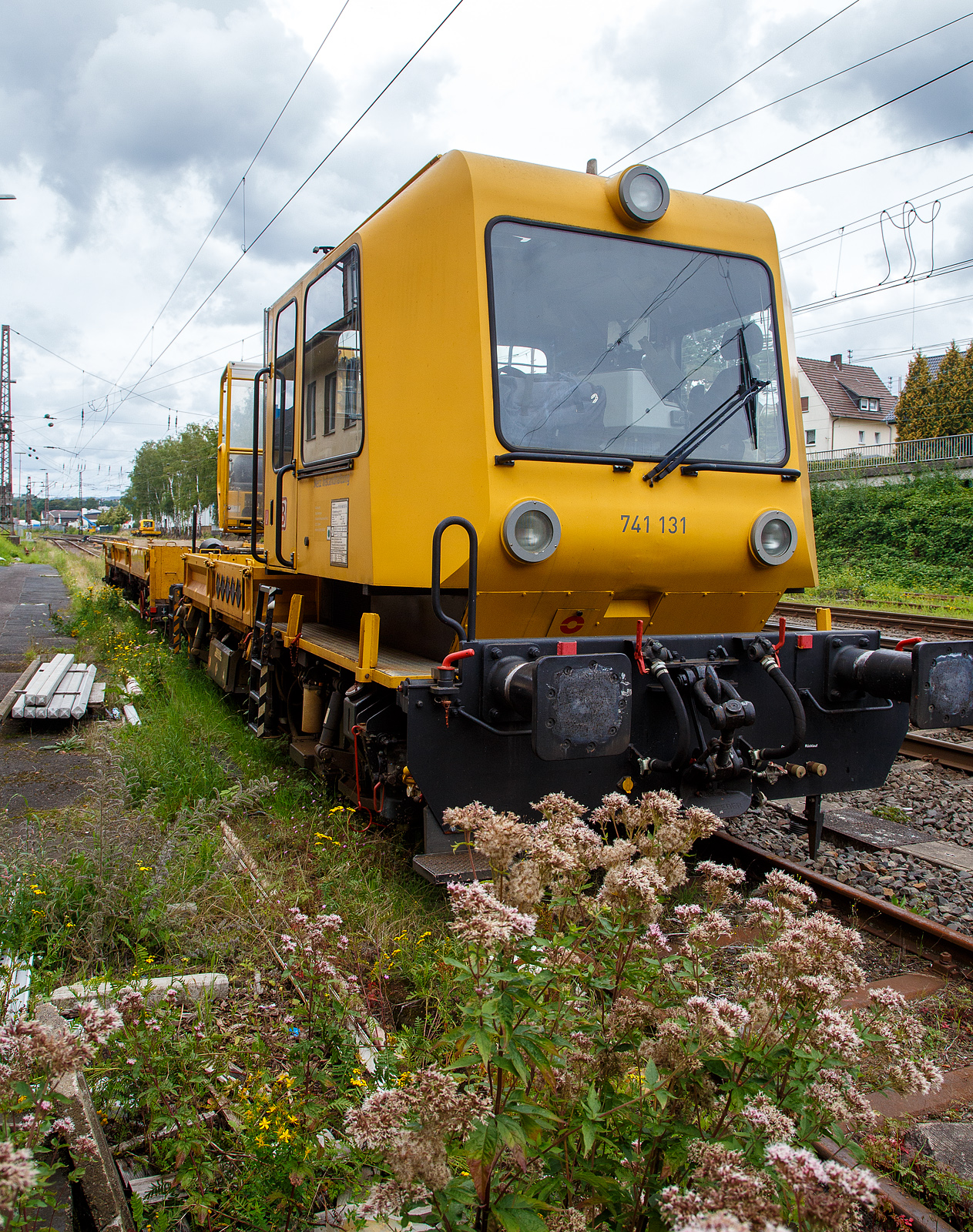 DB 741 131 ein Gleisarbeitsfahrzeug GAF 100 R (Schweres Nebenfahrzeug Nr. 99 80 9420 037-0, ex 97 17 50 011 18-3), mit dem Gleiskraftwagenanhänger H27, Schweres Nebenfahrzeug Nr. D-DB 99 80 9750 276-4 (Anhängerfahrzeug BR 771 725) beide von der DB Netz AG, sind am 13.08.2023 in Kreuztal abgestellt. Da ich kein Fabrikschild finden konnte, kann ich keine ehemalige Nr. zuordnen.

Das GAF 100 R wurde 1996 von GBM (Gleisbaumechanik Brandenburg/H. GmbH) unter der Fabriknummer 52.1.124 gebaut, es hat die EBA Nummer EBA 96 P01 N023.

Das Gleisarbeitsfahrzeuge GAF 100 R ist ein Nebenfahrzeug das von der Firma GBM Gleisbaumechanik Brandenburg/H. GmbH gebaut wurde. Mit ihm können Personen (zur Mitfahrt sind 6 Personen zugelassen), Material und Ausrüstungen befördert werden können. Zudem hat es einen Palfinger PK 9001 Kran.

Der Antrieb des zweiachsigen Fahrzeuges erfolgt von einem 6 Zylinder, wassergekühlten MAM D 0826 LOH 07 Dieselmotor mit 169 kW (230 PS) Leistung über Lastschaltwendegetriebe auf die Radsatzgetriebe.

Technische Daten GAF:
Achsfolge: B
Länge über Puffer: 9.100 mm
Achsabstand: 4.800 mm
Treibraddurchmesser: 750 mm (neu)
Höchstgeschwindigkeit: 100 km/h
Eigengewicht: 16 t
Zul. Anhängelast: 40 t / (80 t mit Regelzugeinrichtung Hg 60 km/h)
Nutzlast : 5,0 t
Zur Mitfahrt zugel. Personen: 6
Der Antrieb des zweiachsigen Fahrzeuges erfolgt von einem 6 Zylinder, wassergekühlten MAN D 0826 LOH 07 Dieselmotor mit 169 kW (230 PS) Leistung über Lastschaltwendegetriebe auf die Radsatzgetriebe.

Der H 27 (Anhänger zu GAF 100) wurde von der GBM (Gleisbaumechanik Brandenburg/H. GmbH) gebaut.

Der GBM beschreibt dieses Fahrzeug wie folgt:
Der Anhänger H 27 wurde im Zusammenhang mit den Nebenfahrzeugen der Gleisbaumechanik Brandenburg entwickelt und ist in Ladeflächenhöhe, Kupplungsausführung sowie Energie - und Pneumatikanschlüssen diesen angepasst. Eine Anpassung an weitere Gerätesysteme ist nach Kundenwunsch möglich. Der Anhänger H 27 dient dem Transport von Baumaschinen, er ist aber auch gut für das Transportieren von Stückgut, Kleinteilen und Schienen geeignet. Der H 27 ist mit einem Paar einhängebarer Auffahrrampen ausgerüstet. Die Montage der Auffahrrampen kann mit 2 Personen realisiert werden. In seinen Abmessungen erfüllt er die Anforderungen nach EBO, Anlage 8. Der H 27 hat eine Spurweite von 1.435 mm. Der Fußboden des H 27 ist so dimensioniert, daß ein Befahren mit Gabelstaplern mit einer Radlast von 30 kN möglich ist. Zu den Fahrzeugenden hin ist der Fußboden geneigt ausgeführt. Dadurch verringert sich die Fußbodenhöhe von 1.000 mm über Schienenoberkante im mittleren Bereich auf 700 mm über Schienenoberkante. Durch angelegte Auffahrrampen ist es möglich, auf den H 27 mit Baumaschinen zu fahren.

Technische Daten Gleiskraftwagenanhänger:
Achsanzahl: 2
Achsabstand: 6.000 mm
Länge über Puffer: 9.750 mm
Höchstgeschwindigkeit: 100 km/h (vorgestellt 80 km/h)
Eigengewicht: 9,3 t
Zul. Anhängelast: 40 t
Nutzlast : 25,0 t