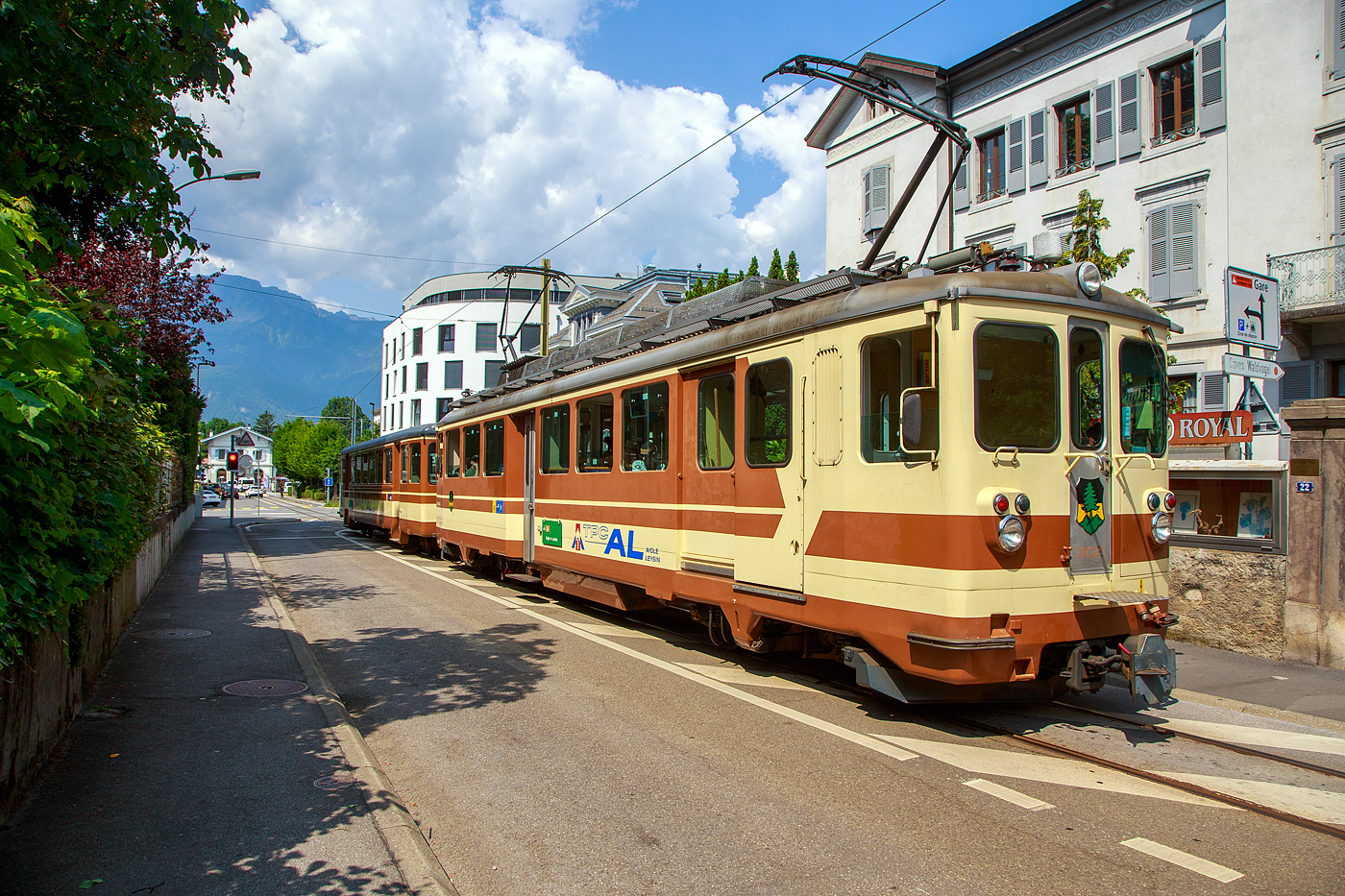 Der AL Regionalzug von Leysin nach Aigle fährt am 28. Mai 2023 (hier als Straßenbahn) durch Altstadt und erreicht bald den Bahnhof Aigle. Der Zug besteht aus dem führenden Steuerwagen AL Bt 351 „Aigle“  und dem Triebwagen AL BDeh 4/4 302 „Leysin“, beide sind noch im ursprünglichen Anstrich der AL (es sind auch die einzigen). 

In Aigle (Waadt) gibt es gleich drei Schmalspurbahnen, die seit 1999 in die Transports Publics du Chablais (TPC) fusioniert worden sind, so machten wir auf unserer Rückreise hier mal einen kurzen Zwischenhalt. Die Schmalspurbahnen sind die Aigle–Ollon–Monthey–Champéry-Bahn (AOMC), die Aigle–Sépey–Diablerets-Bahn (ASD), seit dem 22. Dezember 1913 und die Aigle–Leysin-Bahn (AL).

Die Chemin de fer Aigle–Leysin (AL), deutsch Aigle-Leysin-Bahn, war eine Eisenbahngesellschaft im Schweizer Kanton Waadt. Ihre von 1900 bis 1916 eröffnete 6,2 Kilometer lange Strecke führt von Aigle im Rhonetal hinauf nach Leysin-Grand Hôtel. Die gemischte Zahnradbahn in der Spurweite 1.000 mm (Meterspur) mit dem System Abt wird seit der Betriebsaufnahme elektrisch betrieben. Im Jahr 1999 fusionierte die AL zu den Transports Publics du Chablais (TPC).

Die Bahnstrecke Aigle–Leysin hat ihren Ausgangspunkt vor dem SBB-Bahnhof und führt als Straßenbahn auf der Rue de la Gare (Bahnhofstraße), der Avenue des Ormonts und über die Grande Eau zum Kopfbahnhof Aigle-Dépôt. Dort ändern die Züge die Fahrtrichtung, damit das Triebfahrzeug für die anschließende Bergfahrt am Ende des Zuges eingereiht ist. 

Im Keilbahnhof Aigle-Dépôt beginnt der 5,3 Kilometer lange und bis zu 230 Promille steile Zahnstangenabschnitt. Zunächst führt er durch die Rebberge und bietet den Fahrgästen einen Ausblick auf das Rhonetal. Bei der Haltestelle Pont-de-Drapel wechselt die Vegetation und das Trassee befindet sich nun im Wald. Der Zug erreicht eine Waldlichtung mit dem Bahnhof Rennaz (Leysin), wo er sich in der Regel mit dem Gegenzug kreuzt. Die Strecke führt weiter durch Wald und den 154 Meter langen Tunnel Rennaz. Ab rund 1.200 Meter über Meer fährt die Zahnradbahn durch Weiden und erreicht nach kurzer Zeit den Bahnhof Leysin-Village (Leysin-Dorf). Hier beginnt der Doppelspurabschnitt mit der 128 Meter langen Brücke Leysin nach Leysin-Feydey. Nach dem 287 Meter langen Kehrtunnel Leysin erreicht die Strecke, immer noch mit Zahnstange versehen, den Endpunkt Leysin-Grand Hôtel.


Die Triebwagen und Steuerwagen BDeh 4/4 301–302 und Bt 351–352 wurden 1966 von SIG/SAAS gebaut. 

TECHNISCHE DATEN:
Spurweite: 1.000 mm
Fahrleitungsspannung: 1.500 V =

Triebwagen: BDeh 4/4 301-302
Zahnstangensystem: Abt
Achsfolge: Bo'zz Bo'zz
Länge über Puffer: 16.100 mm
Drehzapfenanstand: 9.540 mm
Achsabstand im Drehgestell: 2.460 mm
Leistung: 596 kW (808 PS)
Treibraddurchmesser: 840 mm (neu)
Zahnrad-Teilkreisdurchmesser: 650
Höchstgeschwindigkeit: 40 km/h
Übersetzung: 1:12,2
Gewicht: 33.0 t
Sitzplätze: 48
Max. Ladegewicht: 1,5 t

Steuerwagen Bt 351–352
Anzahl der Achsen: 4
Gewicht: 11.0 t
Sitzplätze: 48
