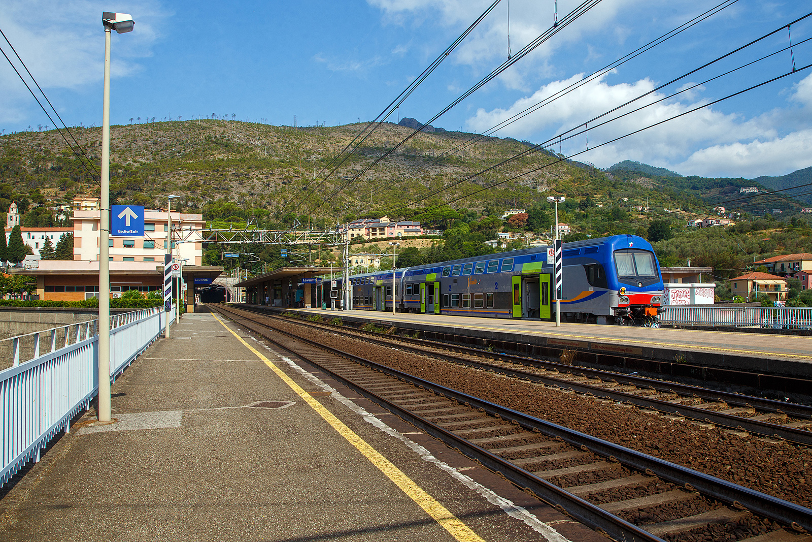 Der Bahnhof Levanto an der Italienischen Riviera (nördlich der Cinque Terre) an der Bahnstrecke Pisa–Genua (RFI Strecke-Nr. 77 / KBS 31 La Spezia–Genua) am 23.07.2022.

Steuerwagen voraus steht hier ein Trenitalia „Vivalto“- Doppelstock-Wendezug, als Cinque Terre Express nach La Spezia, zu Abfahrt bereit. Vorne der Trenitalia „Vivalto“-Steuerwagen 50 83 26-78 957-7 I-TI der Gattung npBH, am Zugschluss war die Trenitalia E.464 578, eine Bombardier TRAXX P160 DCP.

In den letzten Jahren werden bei Trenitalia für RegioExpress-Züge die Vivalto-Wagen eingesetzt, Zuglok ist meist eine E.464 (Bombardier TRAXX P160 DCP). Einige Wagen sind auch bei Trenord und den Ferrovie Emilia Romagna zu finden. Von dieser zweite Serie der CDPTR-Wagen (Carrozza Double Deck for Regional Transport) wurden 350 Wagen ab 2012, gebaut von AnsaldoBreda / Hitachi Rail Italy, in Dienst. Die sechsteiligen Doppelstock-Wendezüge haben eine Kapazität von etwa 1.000 Fahrgästen, darunter 700 Sitzplätze und ein Fahrradabteil. 

Nach der Einführung der neuen DPR-Lackierung bei den Elektrozügen ETR 425  Jazz , basierend auf grau mit blau/orangefarbenen Bändern und grünen Türen, wurde die gleiche Lackierung auch auf andere Fahrzeuge des Fuhrparkeres für Regionalzüge der Trenitalia ausgedehnt, einschließlich der modernen Doppelstockwagen  Vivalto .

Das „Vivalto“-Logo in der Mitte der Seitenteile blieb zunächst auch in der neuen Lackierung unverändert, allerdings mit einem Farbwechsel für die horizontale Linie, um besser mit dem neuen grafischen Design zu harmonieren.