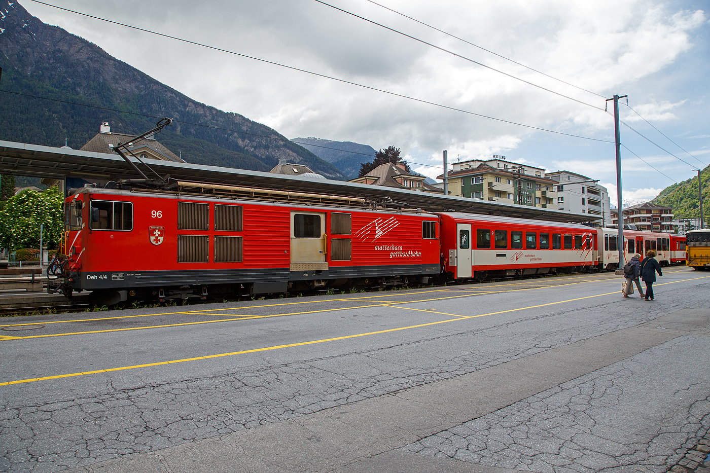 Der Deh 4/4 II - 96  Münster   der Matterhorn-Gotthard-Bahn (MGB), ex FO 96  Münster   (Furka-Oberalp-Bahn), am 25.05.2023 mit einen Regionalzug von Andermatt nach Visp im Bahnhof (Vorplatz) Brig.

Der Gepäcktriebwagen wurde 1984 von SLM (mechanischer Teil, Lokomotivkasten) und BBC (elektrische Ausrüstung) gebaut.

Der Deh 4/4 II ist ein schmalspuriger Gepäcktriebwagen der Matterhorn-Gotthard-Bahn (MGB) für Adhäsions- und Zahnradbetrieb. Weil die Furka-Oberalp-Bahn (FO) mit den Deh 4/4 I gute Erfahrungen gemacht hatte, beschaffte sie die Deh 4/4 II als Nachfolger. Im Zuge des Zusammenschlusses der FO mit der BVZ kamen sie zur neuen Gesellschaft Matterhorn-Gotthard-Bahn, wo sie nur noch als Deh 4/4 bezeichnet und, wenn nötig, anhand der Seriennummern 2.., 5.. und 9.. unterschieden werden.
