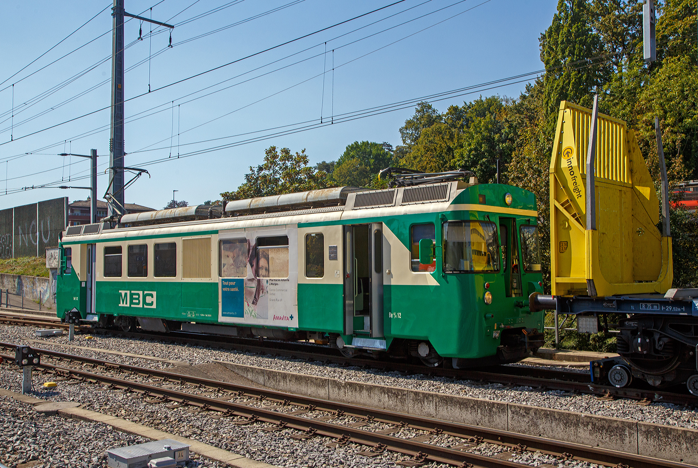 Der elektrische Schmalspur Güterzug-/Personentriebwagen MBC/BAM Be 4/4 12 rangiert, am 07 September 2023 an einer Rollbockgrube beim Bahnhof Morges, den leeren 2 x vierachsiger Flachwagen in Sonderbauart (INNOFREIGHT Holz-Doppelwagen) 37 80 4657 028-9 D-VTG der Gattung Sggmrrs S240, auf schmalspurige Rollböcke vom Typ Vevey.

Die Be 4/4 Triebwagen:
Im Jahre 1978 bestellten die BAM und die YSteC je drei Triebwagen Be 4/4 11–13 bzw. 1–3. 1980 konnte die Bestellung um fünf passende Steuerwagen Bt 51–53 (BAM) und 51–52 (YSteC) ergänzt werden. Die Be 4/4 sind sechs meterspurige vierachsige Elektrotriebwagen, die 1981 von den Ateliers de constructions mécaniques de Vevey (ACMV) an die Chemin de fer Bière–Apples–Morges (BAM) und Chemin de fer Yverdon–Ste-Croix (YSteC) geliefert wurden. Die Drehgestelle wurden von SIG und die Elektrik von SAAS (Société Anonyme des Ateliers de Sécheron) der ACMV zugeliefert. Wegen der Übernahme der Sécheron-Werke durch die BBC wurde die elektrische Ausrüstung jedoch in Oerlikon montiert. Die Steuerwagen wurden 1982 ausgeliefert.

Mit ihrer Leistung von 780 kW und einem Dienstgewicht von 44 Tonnen sind sie auch zur Beförderung schwerer Rollbock-Züge geeignet. Die zulässige Anhängelast beträgt 200 Tonnen auf 35 ‰ Steigung. 

Die BAM Triebwagen besitzen  +GF+-Kupplungen, die das selbsttätige Kuppeln auch in den Kurven ermöglichen. Hier für die Rollbock-Züge besitzen die Triebwagen eine spezielle Kuppelstange. 

Die BAM änderte 2003 ihren Namen in Transports de la région Morges–Bière–Cossonay (MBC).

TECHNISCHE DATEN:
Hersteller:  ACMV, SIG, SAAS
Baujahr: 1981
Spurweite: 1.000 mm (Meterspur)
Achsfolge: Bo' Bo'
Länge über Puffer: 18.750 mm
Drehzapfenabstand: 12.480 mm
Treibraddurchmesser:  750 mm (neu)
Höhe: 4.100 mm
Breit: 2.650 mm
Dienstgewicht: 46 t
Höchstgeschwindigkeit: 75 km/h
Leistung: 780 kW
Anzahl der Fahrmotoren: 4
Fahrleitungsspannung: 15.000 V, 16.7 Hz ~
Sitzplätze: 40 (2. Klasse)
Steuerung: Vielfachsteuerung
Kupplungstyp: +GF+ bei BAM (bei der YSteC Mittelpuffer Zp2) 

Der Güterverkehr der BAM:
Bei der Betriebseröffnung besaß die BAM rund ein Dutzend schmalspurige Güterwagen, eigentlich recht wenig. Obwohl die Trassierung problemlos den Rollschemelbetrieb erlaubt, wurde dieser erst 1965 eingeführt. 1981 ging die BAM zum zum Rollbock-System Vevey über, hierbei wird die Achse des Normalspurwagens nicht mehr fixiert. Der Wagen steht mit seinen Rädern in speziell geformten Mulden. Derartige Rollböcke – als System Vevey von den Ateliers de constructions mécaniques de Vevey (ACMV) in Serie gefertigt – werden bei mehreren Bahnen in der Schweiz und einer Bahn in Deutschland eingesetzt. Der Hauptunterschied zum klassischen Rollbock ist, dass das Aufbocken bei langsamer Fahrt automatisch geschieht. Somit sind zahlreiche Unannehmlichkeiten und Gefährdungspotenziale behoben. Zudem konnten damit bei der BAM auch die etwas höheren Panzer 87 (Leopard 2) transportiert werden.

Die schmalspurigen Güterwagen wurden veräußert oder zum großen Teil bereits 1976 bis 1978 abgebrochen. Seit den 1990er Jahren wird der Güterverkehr fast ausschließlich mit Normalspurwagen abgewickelt. Zu Beginn der 2010er Jahre transportierte die BAM jährlich rund 40 000 Tonnen Güter, vorwiegend Armeepanzer, Zuckerrüben und Getreide. Im Herbst 2013 nahm sie den Transport von etwa 170 000 Tonnen Kies pro Jahr aus Apples nach Morges und weiter auf der SBB-Strecke nach Gland auf. Um die Kiesgrube auszufüllen, befördert die MBC in der Gegenrichtung 100 000 Tonnen Aushubmaterial. 


Im Jahre 1978 bestellten die BAM und die YSteC je drei Triebwagen Be 4/4 11–13 bzw. 1–3. 1980 konnte die Bestellung um fünf passende Steuerwagen Bt 51–53 (BAM) und 51–52 (YSteC) ergänzt werden. Die Be 4/4 sind sechs meterspurige vierachsige Elektrotriebwagen, die 1981 von den Ateliers de constructions mécaniques de Vevey (ACMV) an die Chemin de fer Bière–Apples–Morges (BAM) und Chemin de fer Yverdon–Ste-Croix (YSteC) geliefert wurden. Die Drehgestelle wurden von SIG und die Elektrik von SAAS (Société Anonyme des Ateliers de Sécheron) der ACMV zugeliefert. Wegen der Übernahme der Sécheron-Werke durch die BBC wurde die elektrische Ausrüstung jedoch in Oerlikon montiert. Die Steuerwagen wurden 1982 ausgeliefert.

Mit ihrer Leistung von 780 kW und einem Dienstgewicht von 44 Tonnen sind sie auch zur Beförderung schwerer Rollbock-Züge geeignet. Die zulässige Anhängelast beträgt 200 Tonnen auf 35 ‰ Steigung. 

Die BAM Triebwagen besitzen  +GF+-Kupplungen, die das selbsttätige Kuppeln auch in den Kurven ermöglichen. Hier für die Rollbock-Züge besitzen die Triebwagen eine spezielle Kuppelstange. 

Die BAM änderte 2003 ihren Namen in Transports de la région Morges–Bière–Cossonay (MBC).