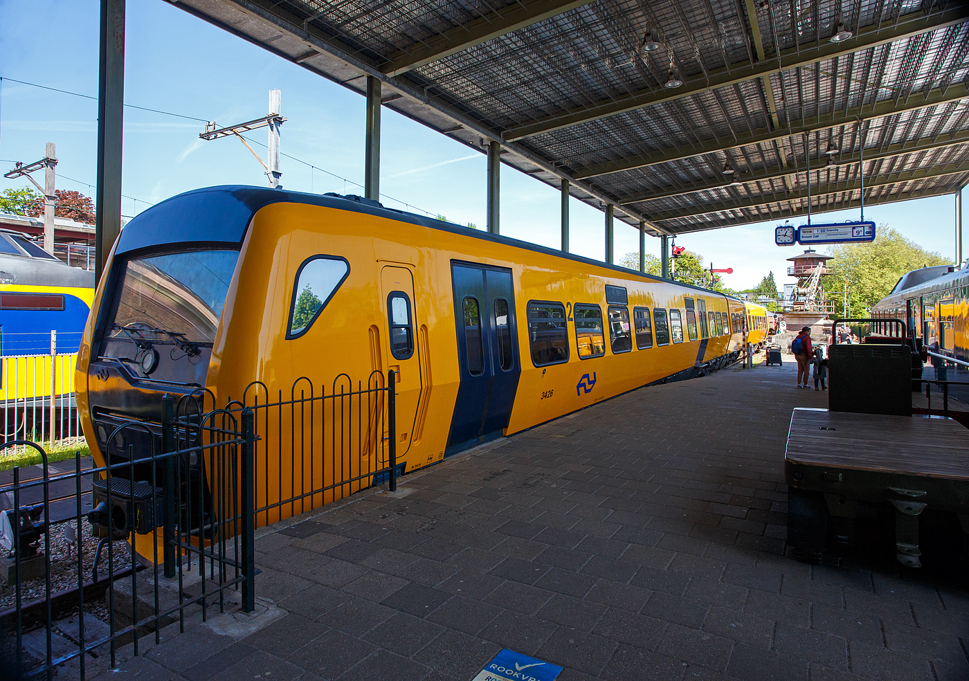 Der zweiteilige Dieseltriebwagen NS 3426 „Buffel“, deutsch Büffel, NL-NS 95 84 5131426-6, (Bk 3426 + ABk 3426), der NS Baureihe/Serie DM '90 (Dieselmaterieel '90), am 29 April 2025 im Het Spoorwegmuseum (bis 2005 NSM - Nederlands Spoorwegmuseum / Niederländischen Eisenbahnmuseum) in Utrecht im Bahnhof Maliebaanstation. Ein sehr schönes Eisenbahnmuseum das zum Verweilen einlädt, leider fehlte uns dieses Mal die Zeit dafür. 

Der diesel-hydraulische Triebzug wurde 1998 von der Waggonfabrik Talbot GmbH & Co. (heute Bombardier) in Aachen (D) für die NS - Nederlandse Spoorwegen N.V. (Niederländische Eisenbahnen AG) gebaut und geliefert. Die komplette elektrische Ausrüstung, sowie die Zugsteuerungs- und Diagnosefunktionen, durch Holec in Ridderkerk (NL), heute Alstom. Die Innenausstattung wurde von DUEWAG (Düsseldorfer Waggonfabrik) in Krefeld (D), heute Siemens, gefertigt und von dort aus wurden die Züge auch in die Niederlande transportiert. Der Büffel bzw. Triebzug 3426 ging 2017 außer Betrieb und wurde Anfang 2018 an das Eisenbahnmuseum übergeben.

Dieselmaterieel '90 (DM '90):
Die zweiteiligen Dieseltriebwagen der NS-Serie Dieselmaterieel '90 (DM '90), offiziell Buffel (Büffel) genannt, da die Frontform an einen Büffelkopf erinnert, war eine Serie aus 53 zweiteiligen Dieseltriebwagen die von Waggonfabrik Talbot in Aachen gebaut wurden. Die Triebzüge basieren teilweise auf dem Stoptrein-Material '90, dem „Railhopper“. Die Buffels wurden ab 1996 von der Niederländischen Eisenbahn und ab 1999 von Syntus eingesetzt. Die letzten Züge der Niederländischen Eisenbahn waren bis 2017 im Einsatz.

Die Büffel waren auf nichtelektrisierten Regionalbahnstrecken der NS in den Niederlanden im Einsatz. Heute verkehren auf diesen Bahnstrecken andere private Eisenbahngesellschaften (wie u.a. Syntus, Arriva und Connexxion) und nicht die NS. So braucht die NS keine Dieselzüge mehr und verabschiedete sich vom Büffel.

Ausstattung und Technik:
Wie der elektrische Triebzug Stoptreinmaterieel '90 (auch von Talbot gebaut), der die Grundlage für den Büffel bildete, weist der DM'90 eine etwas andere gestaltete maximale Breite von 3,20 Metern auf. Durch seine geschickte Gestaltung der Wagenkästen mit gekrümmten Seitenwänden) und die Begrenzung des seitlichen Federwegs ist es möglich, das Wagenprofil 30 Zentimeter breiter als bei den meisten Zügen zu machen und dabei immer noch das Standardprofil einzuhalten. Durch diese Breit wäre es möglich gewesen, in der zweiten Klasse fünf Sitzplätze nebeneinander zu schaffen, was jedoch nicht umgesetzt wurde. Angetrieben wird DM'90 von zwei 6-Zylinder-Reihen-Dieselmotoren von Cummins (Typ NTA 855 R4) mit einer maximalen Leistung von jeweils 320 kW. Das Getriebe von Voith (Typ T211 rzze) ist hydrodynamisch (Voith, Typ T211 rzze). Der DM'90 hat eine Höchstgeschwindigkeit von 140 km/h. Der Büffel konnte in Mehrfachtraktion mit der älteren (ebenfalls dieselhydraulischen) Wadloper (DH1 und DH2) fahren, allerdings war die Höchstgeschwindigkeit dann auf die des Wadlopers von 100 km/h begrenzt. Der Büffel bot 135 Passagieren Sitzplätze (123 in der zweiten Klasse und 12 in ersten Klasse). Als Drehgestelle dienten die Typen RMO 9000 (von Stork RMO Werkspoor), die auch für die doppelstöckigen Interregio-Züge verwendet wurden. Ursprünglich sollten die DM‘90 den gleichen Kopf wie SM‘90 haben, auf Anraten der Marketing- und Designabteilung wurde jedoch der stromlinienförmige Kopf verwendet, der eigentlich schon für SM‘90 entwickelt worden war und Reisende stärker ansprechen sollte.

Die Kombination aus Scheibenbremsen und der ruhige Lauf führte zu einer schlechten Erkennung der Ausrüstung. Auf den Strecken, auf denen die DM'90 verkehrte, installierte der Bahnbetreiber häufig Achszähler. 

TECHNISCHE DATEN:
Serie: NS 3400 - DM '90 (Dieselmaterieel '90) „Buffel“
Gebaute Anzahl: 53
Nummerierung: 3401-3453
Typ: diesel-hydraulischer Triebzug
Baujahre: 1996 bis 1998
Ausmusterung: 2017
Hersteller: Waggonfabrik Talbot GmbH & Co. in Aachen (D), heute Bombardier
Zulieferung elektrische Ausrüstung: Holec in Ridderkerk (NL), heute Alstom
Zulieferung Innenausstattung: DUEWAG in Krefeld (D), heute Siemens
Spurweite: 1.435 mm (Normalspur)
Achsfolge: 2'B' + B'2' (8 Achsen in 4 Drehgestellen)
Zusammensetzung: Bk + ABk

Länge über Kupplung: 52.340 mm
Breite: 3.200 mm
Höhe: 4.142 mm
Treib- und Laufraddurchmesser: 920 mm (neu) / 840 mm (abgenutzt)
Achsabstand im Triebdrehgestell: 2.750 mm
Achsabstand im Laufraddrehgestell: 2.600 mm
Motoren: 2 Stück Cummins 6-Zylinder-Reihen-Dieselmotoren vom Typ NTA 855 R4
Motorleistung: 2 x 340 KW = 640 kW (870 PS)
Getriebe: 2 Stück hydrodynamisches Turbogetriebe von Voith vom Typ T211 rzze
Höchstgeschwindigkeit: 140 km/h
Beschleunigung: 0,6 m/s²
Bremsverzögerung: 1,2 m/s² 
Eigengewicht: 95,2 t 
Fußbodenhöhe: 1.160 mm 
Anzahl der Doppeltüren je Seite: 4 [zweiteilige Pneumatische Pendeltüren 1.300 mm breit]
Sitzplätze (gesamt): 135
Sitzplätze in der 1. Klasse: 12
Sitzplätze in der 2. Klasse: 123
Anzahl der Klappsitze: 34
Stehplätze (4 Pers./m²): 156
Tankvolumen: 2 x 1.000 = 2.000 Liter
Kupplung: Scharfenberg

Verkäufe:
32 Triebzüge wurden 2020 an die SKPL - Stowarzyszenie Kolejowych Przewozów Lokalnych (Vereinigung von Lokalbahnbetrieben) nach Polen verkauft, wo sie nach Modifizierungen seit 2024 als SD85 im Einsatz sind. 

14 Triebzüge wurden 2021 an die Firma Brouwer in Blerick (bei Venlo) verkauft, die diese konnte sie an die rumänische Betreiber Ferotrans-TFI verkaufen.

1 Triebzug (3452) wurde im Januar 2021 an die HTFSE Happy Train Fleet Services B.V. verkauft. Dieser Zug soll zukünftig wieder fahrbereit gemacht werden.

Von den 53 Zuggarnituren wurden letztlich 47 verkauft. 
5 Triebzüge (3403, 3405, 3409, 3410 und 3424) wurden aus unterschiedlichen Gründen verschrottet. 
Der Triebzug 3426 wurde an das Eisenbahnmuseum übergeben.
